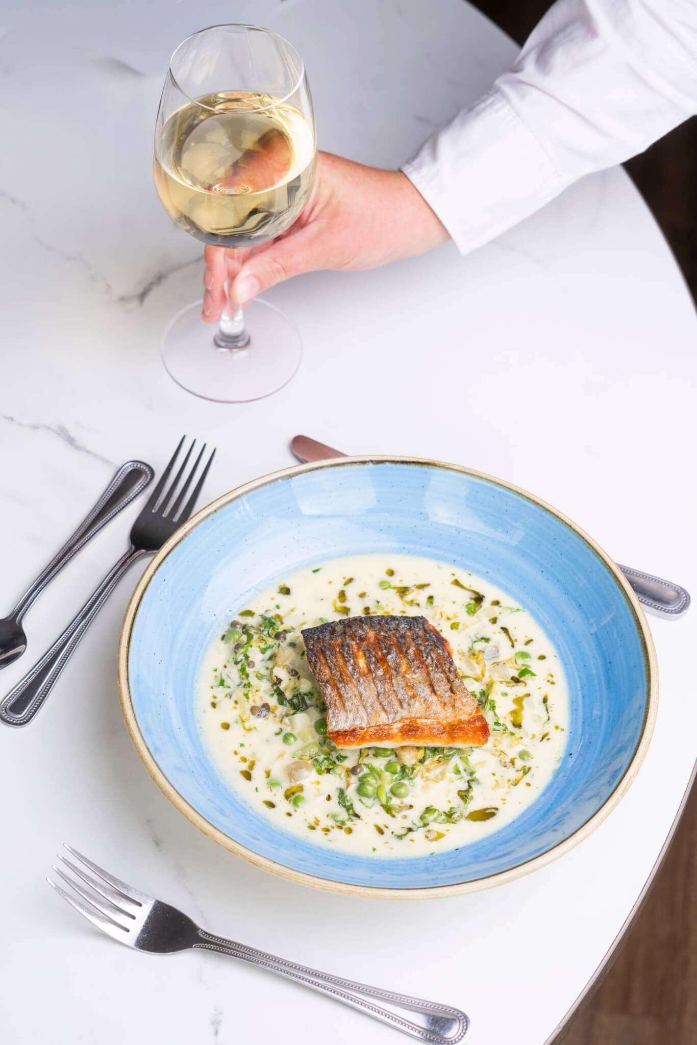 Sea bass fillet with peas and greens, served with white wine