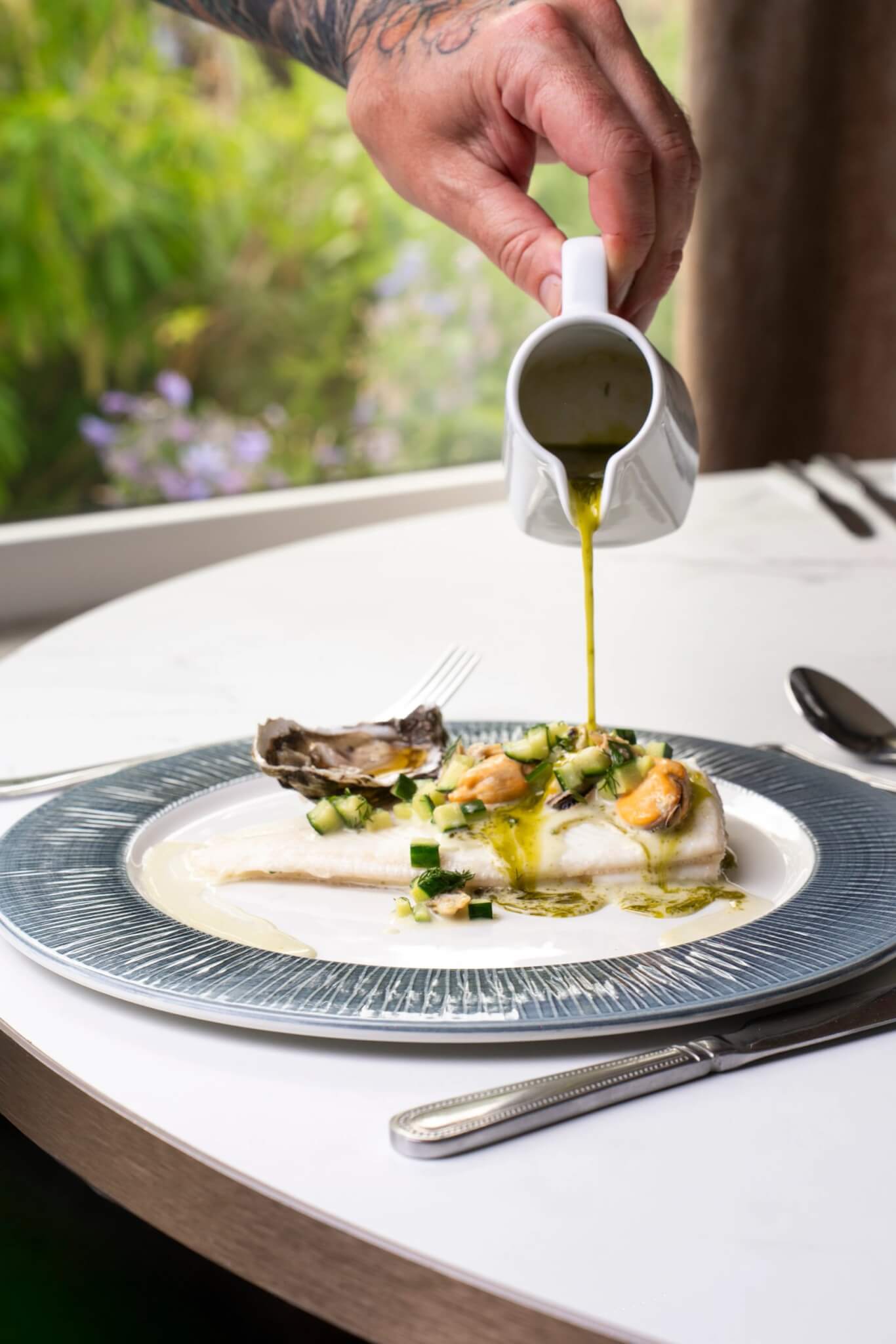 Sole a la Normande with a herb sauce being poured at the table