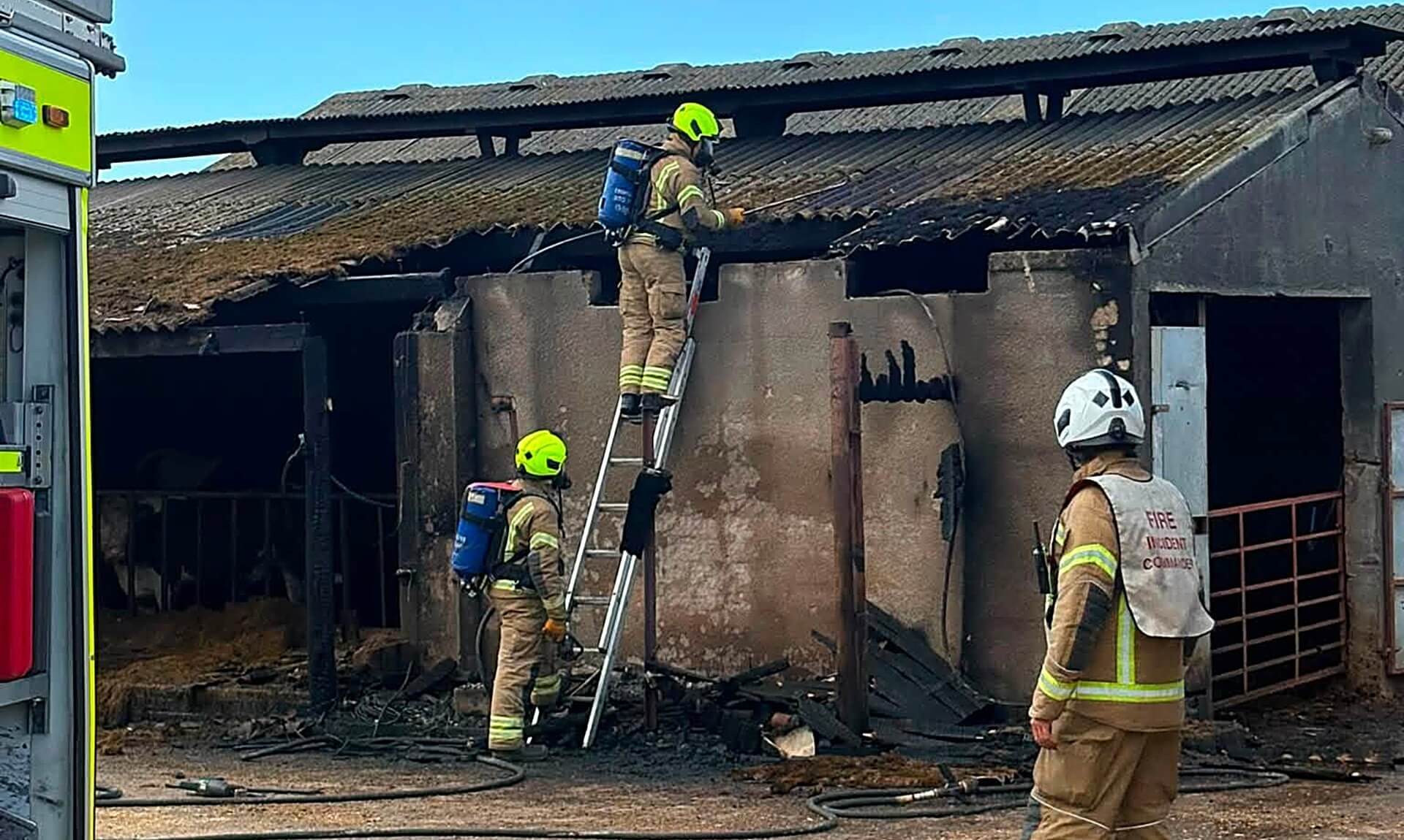Firefighters tackle a barn fire near Bude with a ladder and breathing apparatus