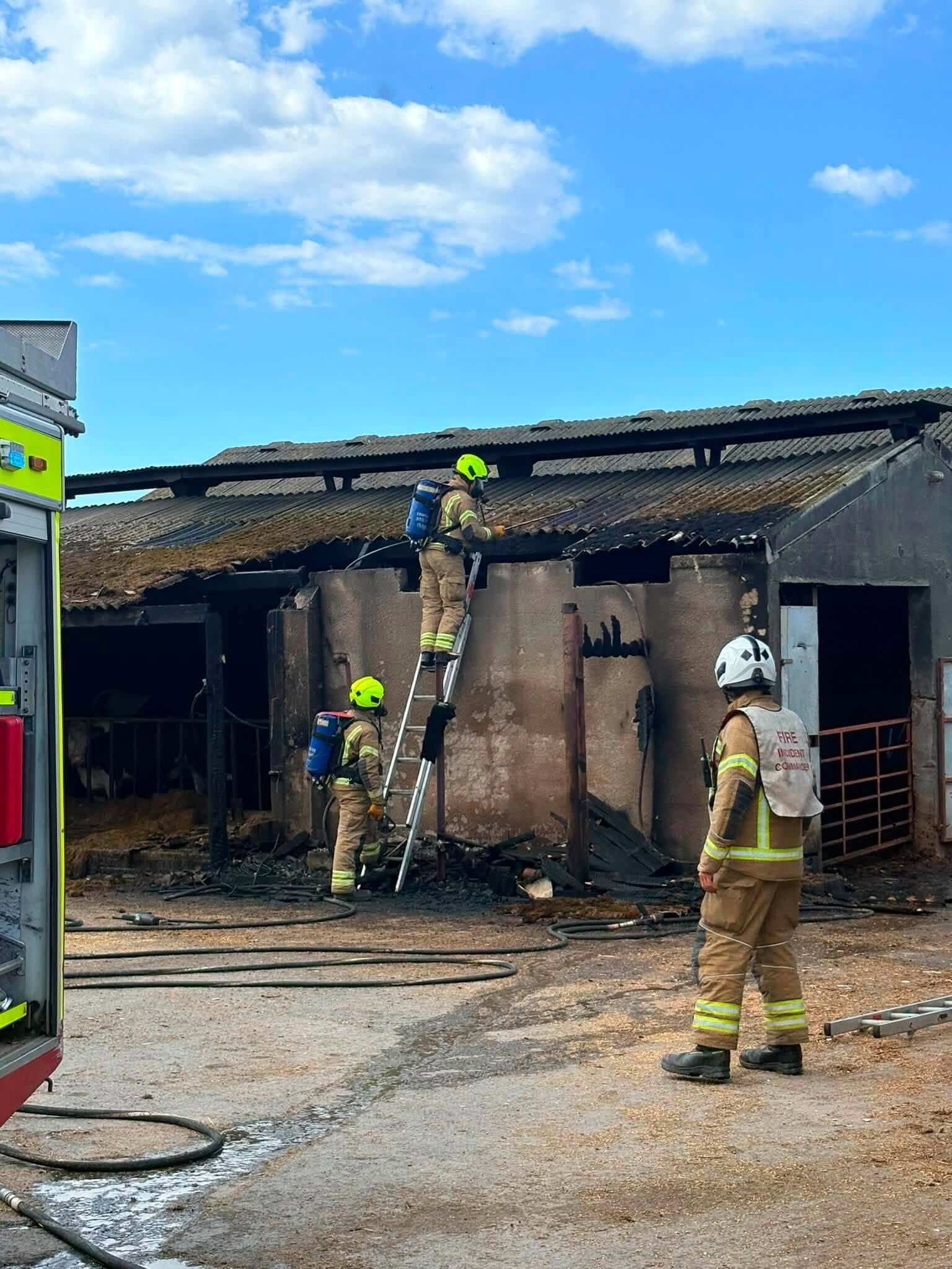 Firefighters tackle a barn fire near Bude with a ladder and breathing apparatus