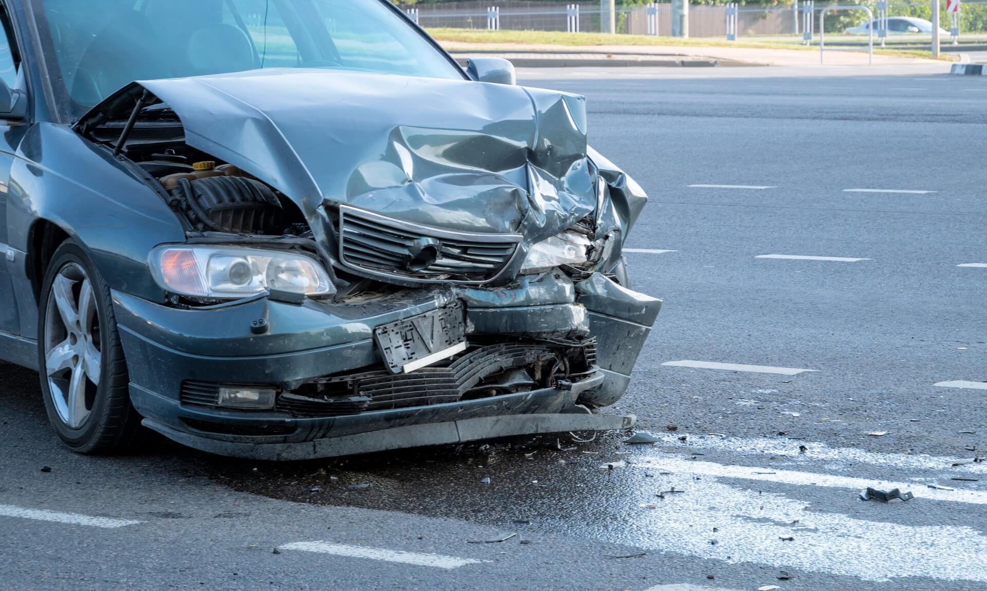 Front end of a car badly damaged after a road collision