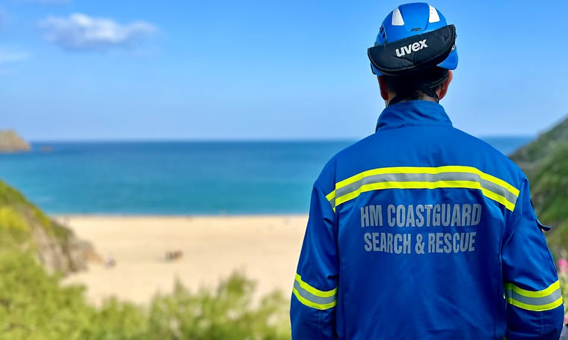 An HM Coastguard Search and Rescue officer looking out over Porthcurno beach in Cornwall