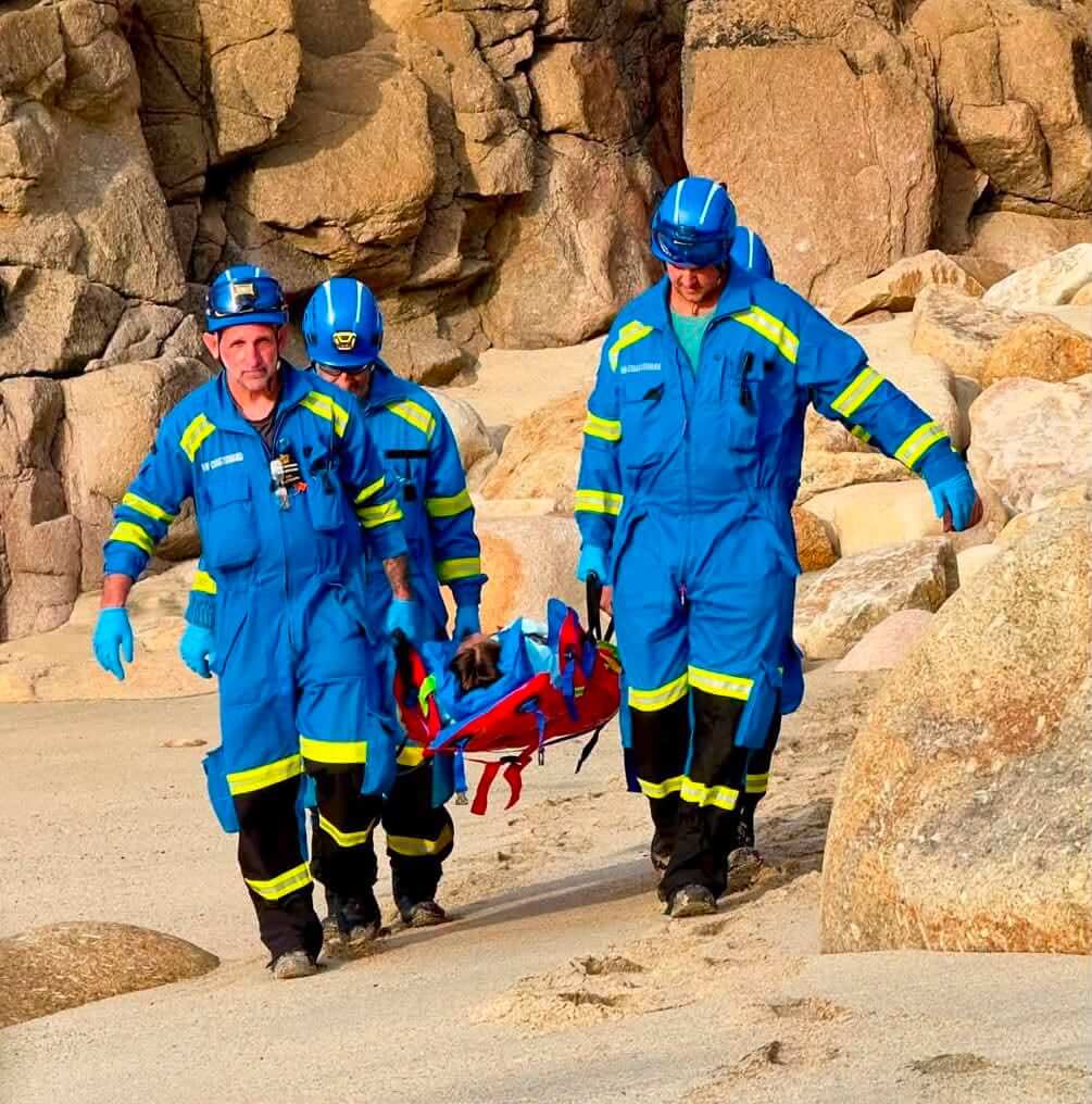Coastguard team carrying a casualty on a stretcher over rocks