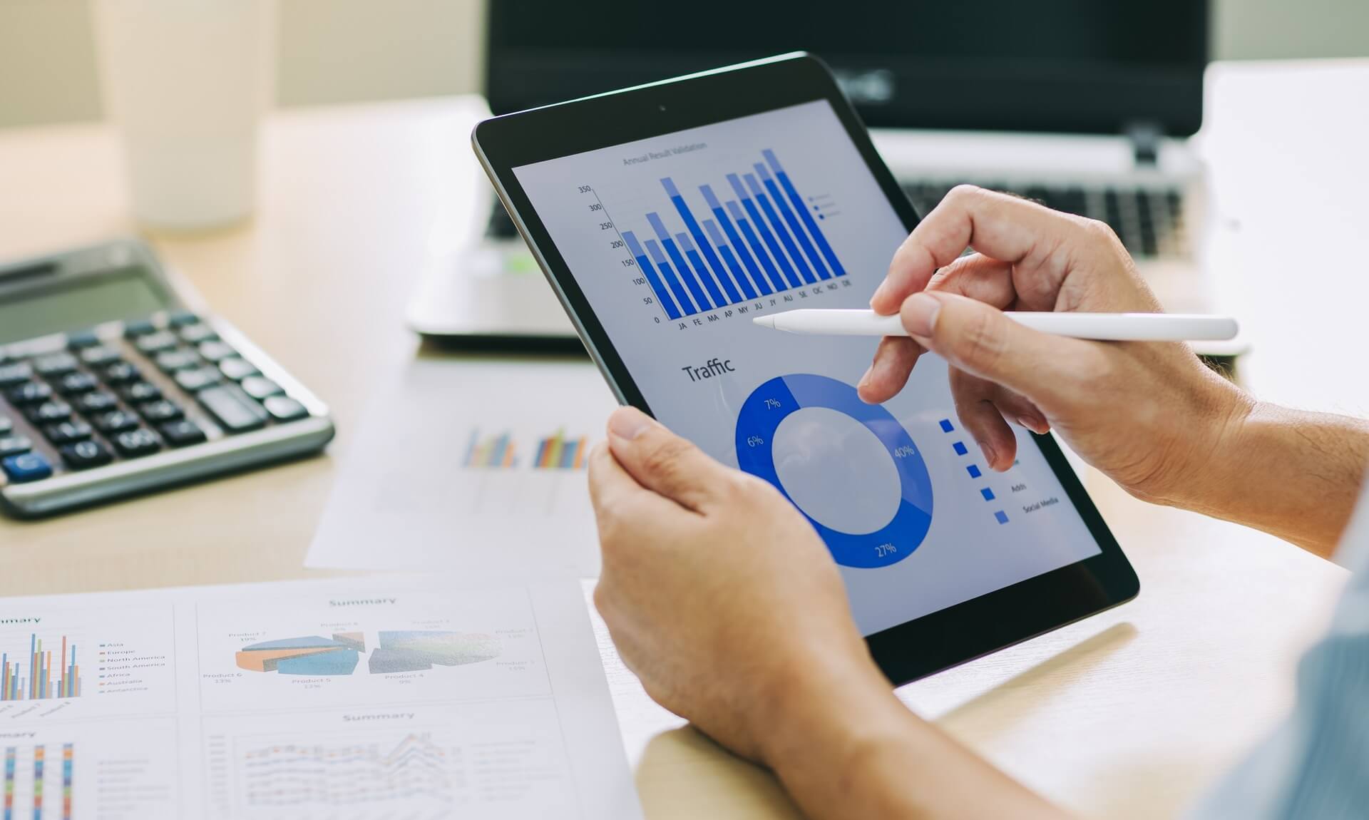 Person reviewing business charts and traffic data on a tablet at a desk