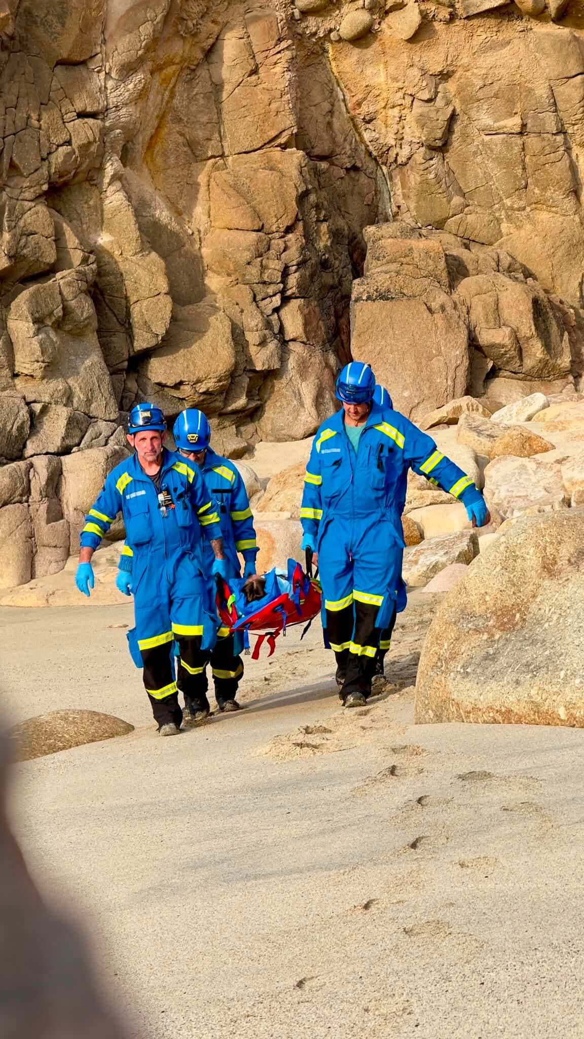Coastguard crew carrying a casualty on a stretcher over rocks