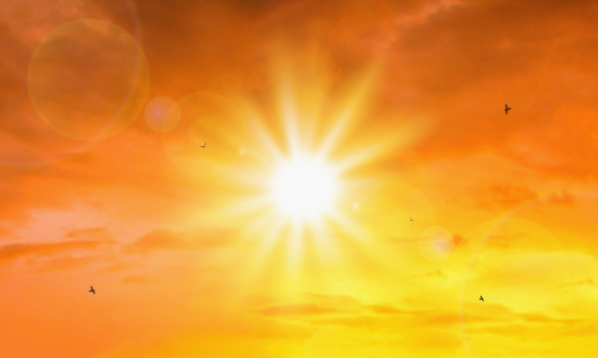 Bright sun blazing in an orange and yellow sky over Cornwall during hot weather