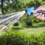 Person using a garden hosepipe spray gun to water a garden