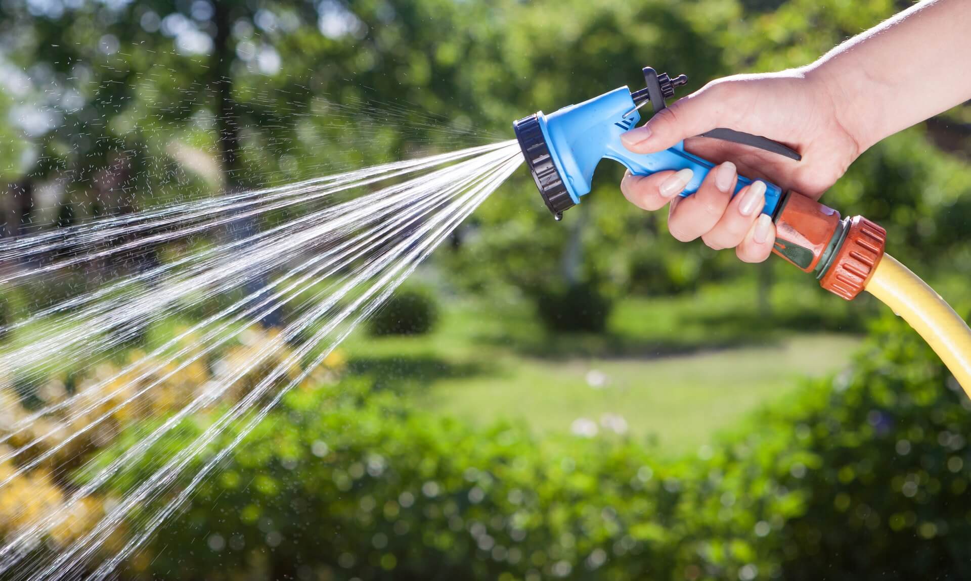 Person using a garden hosepipe spray gun to water a garden