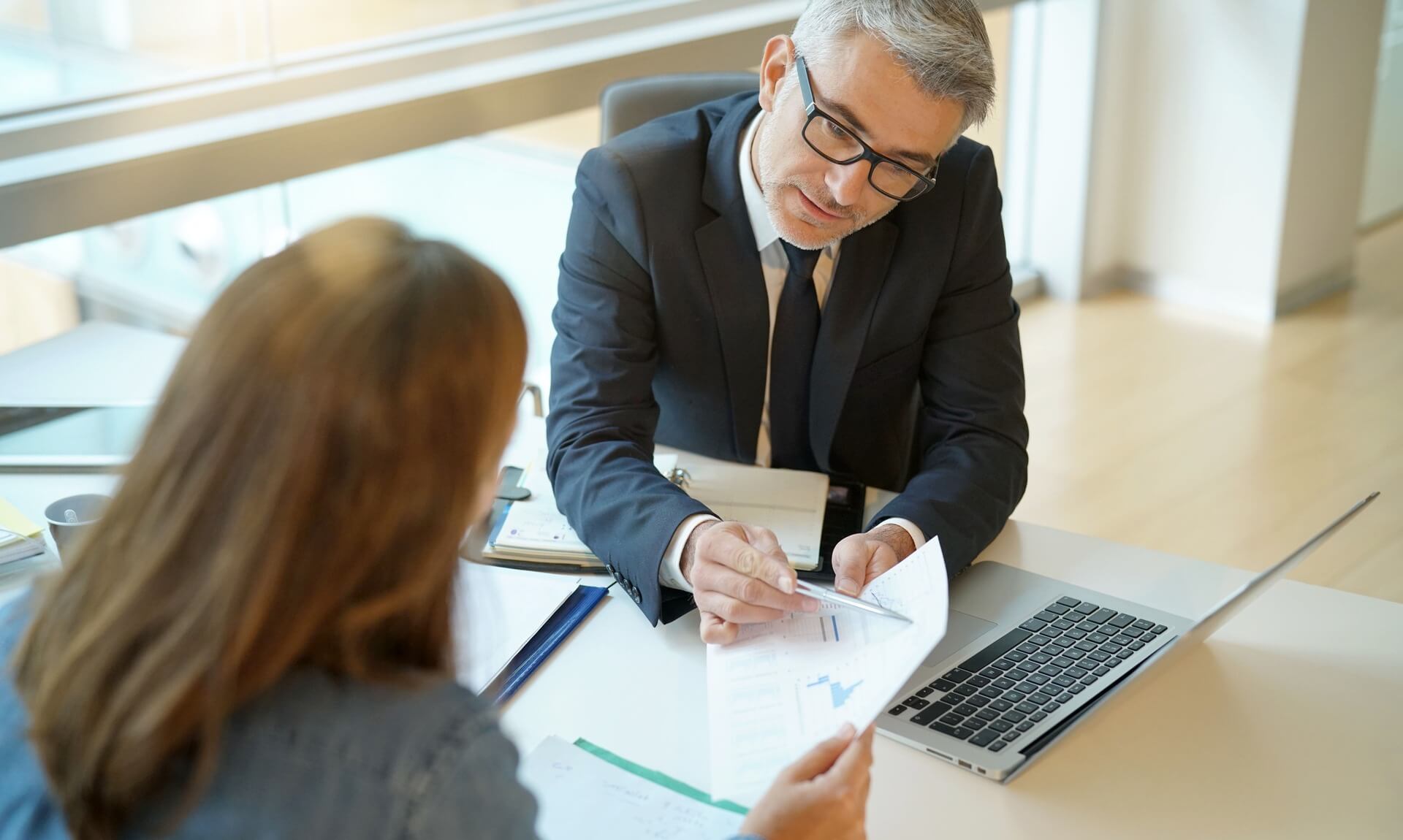 Business adviser in a suit going through financial charts with a client across a desk