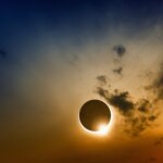 Ring of light around a partial solar eclipse in a cloudy sunset sky