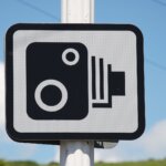 A speed camera warning sign against a blue sky in Cornwall