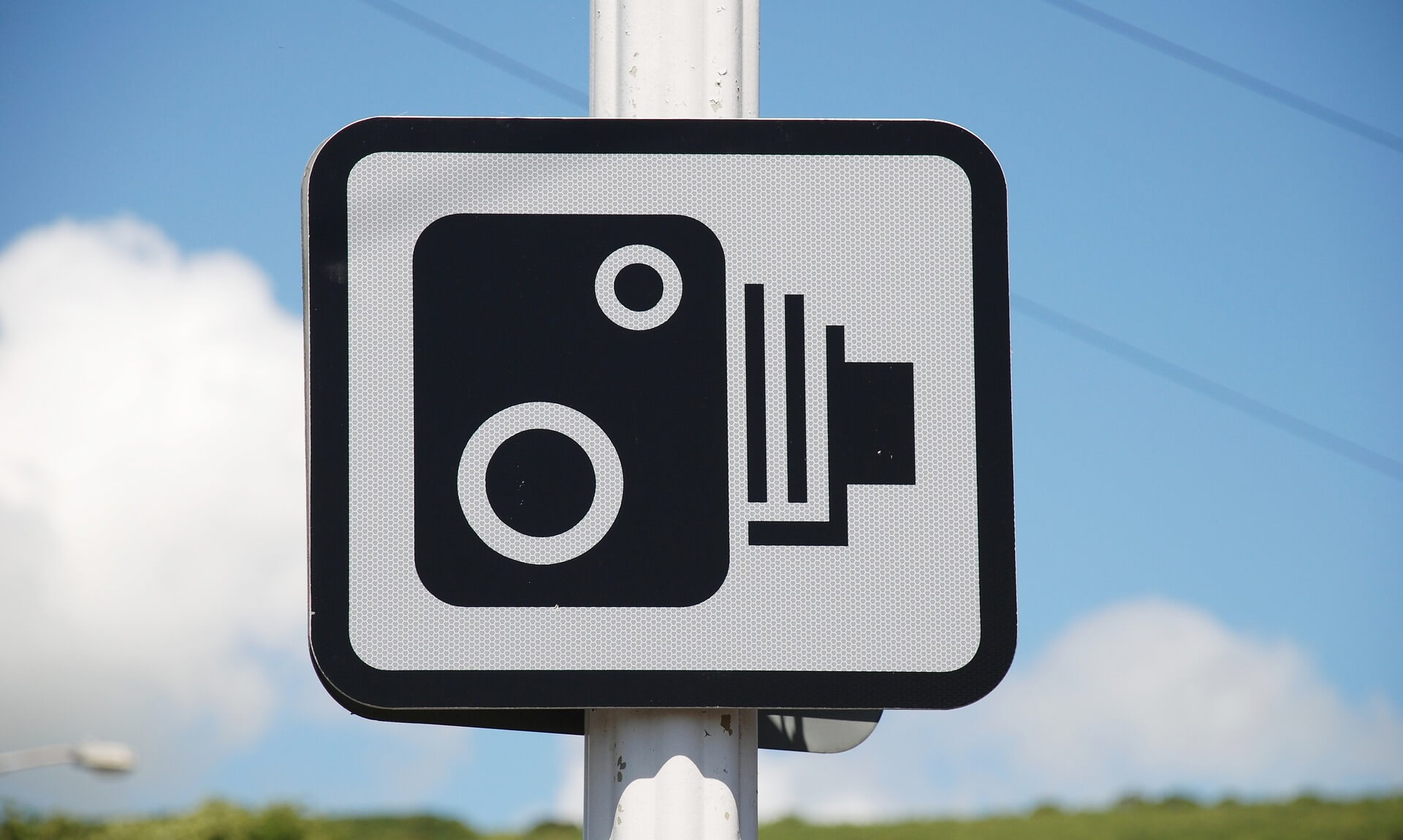 A speed camera warning sign against a blue sky in Cornwall