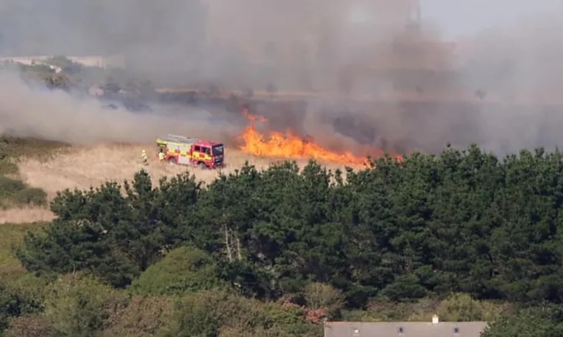 Cornwall Fire and Rescue Service fire engine beside wildfire flames at Mawgan Porth