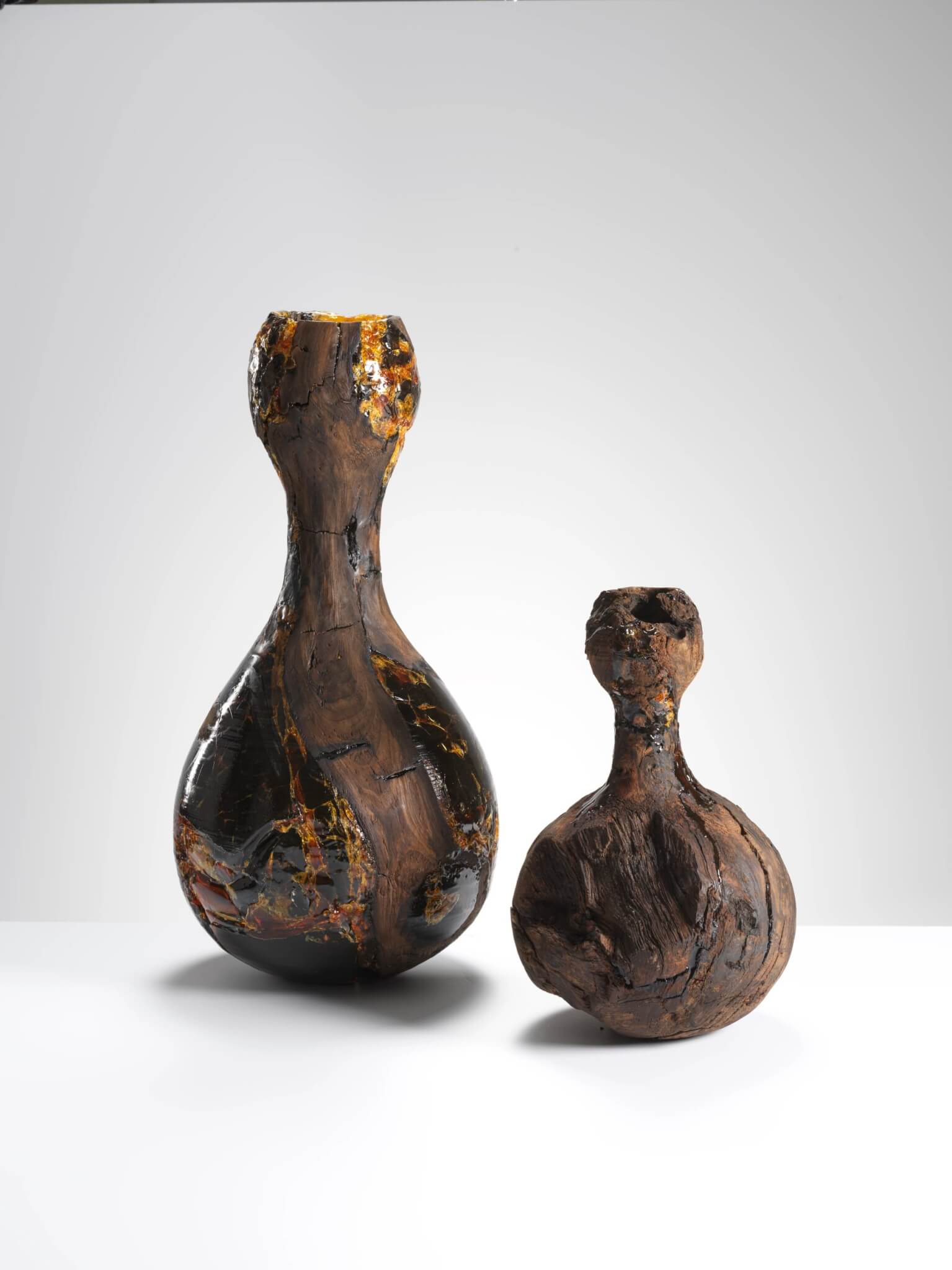 Two dark, glossy carved wooden vessels by Eleanor Lakelin on a white background