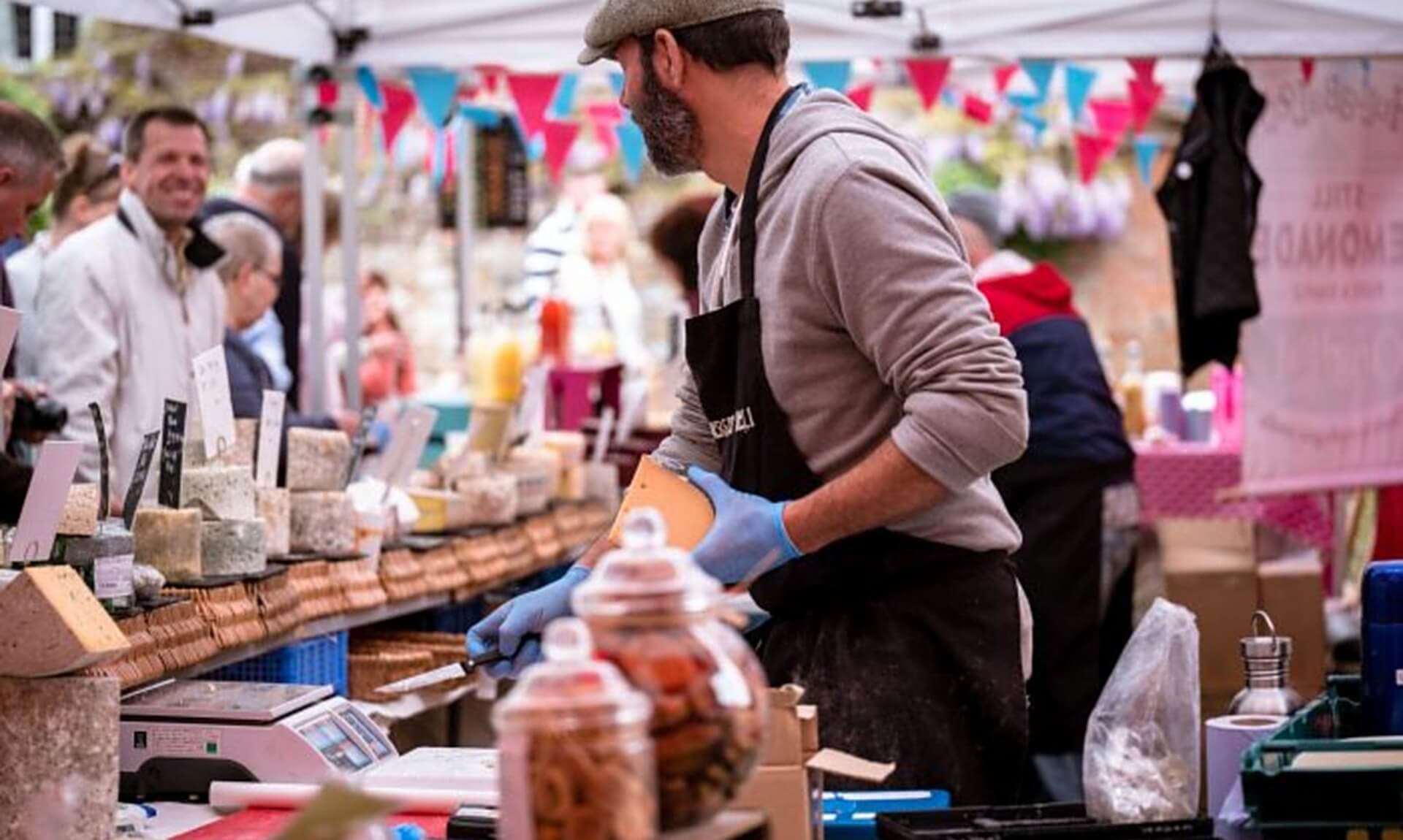 Trader serving cheese at a Cornish market stall
