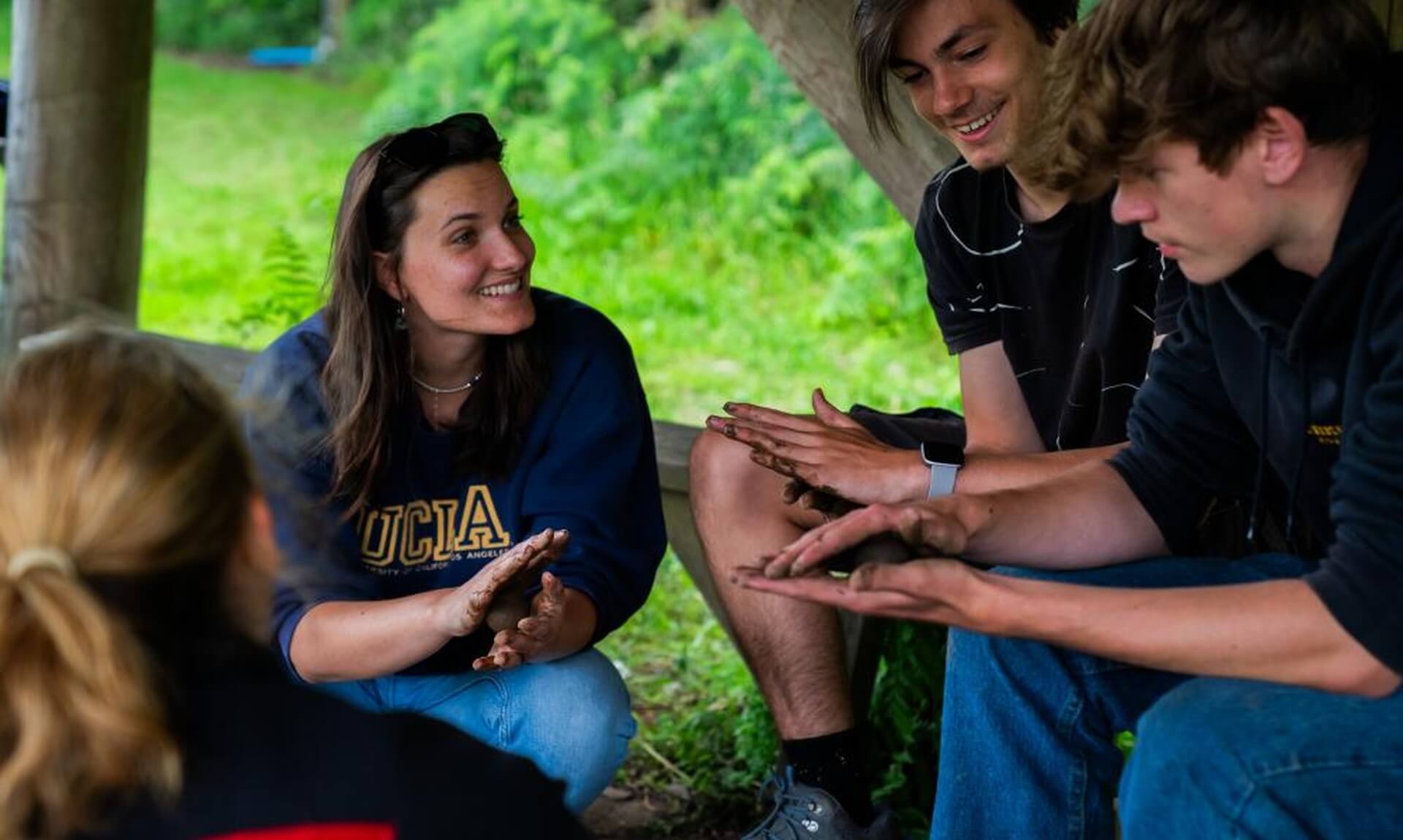 Young people sitting together with muddy hands during a nature activity at the Eden Project