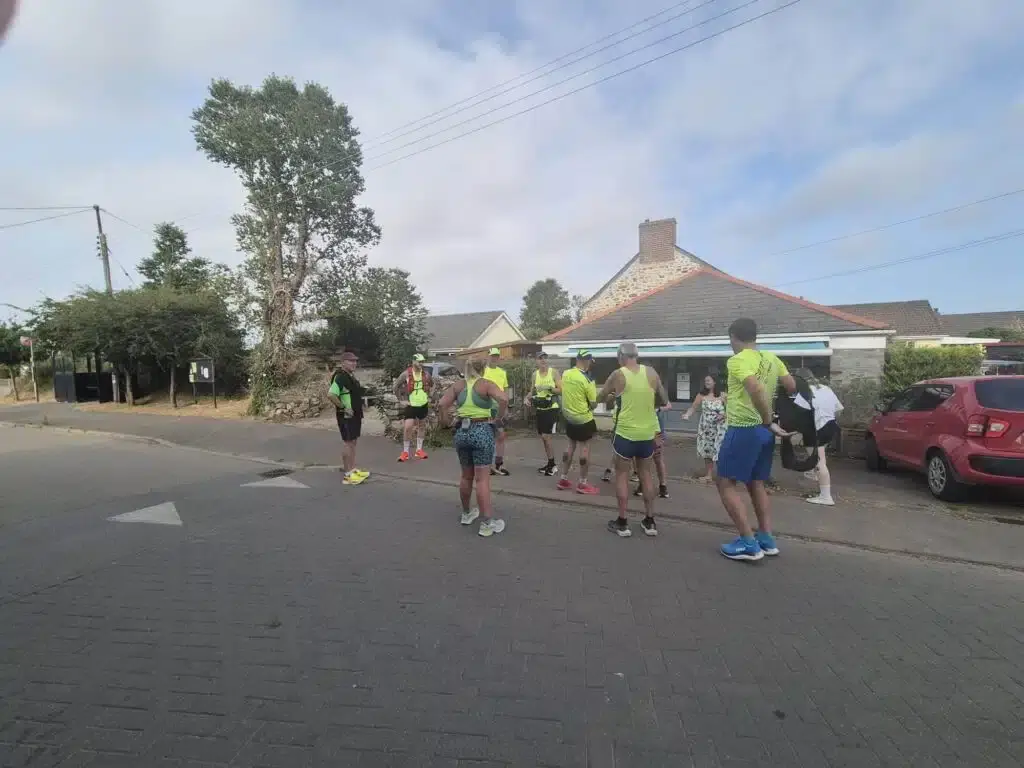 Carn Runners gathering by a village shop at a changeover point