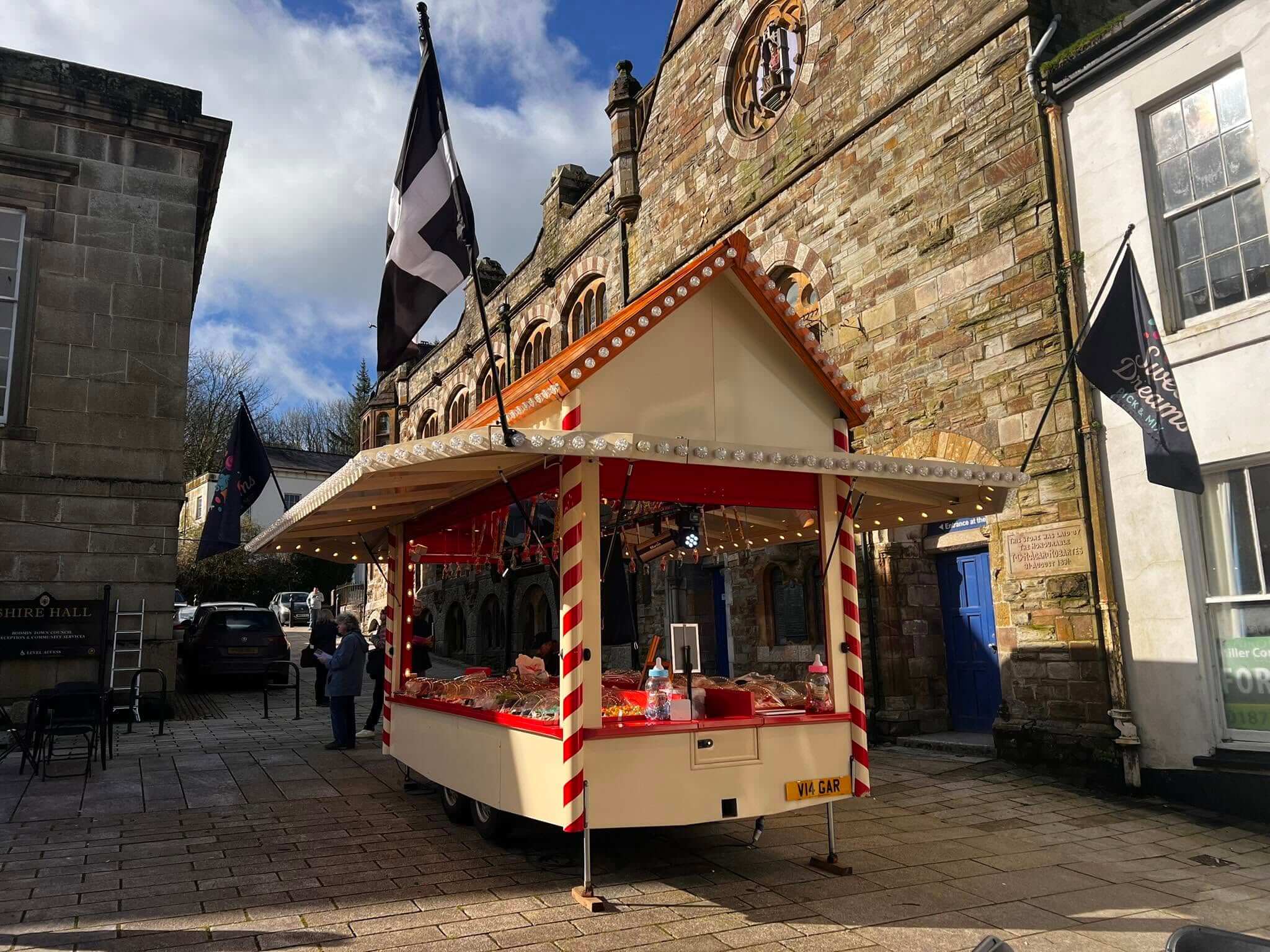The Sweet Dreams sweet stall lit up beside Shire Hall with a Cornish flag flying