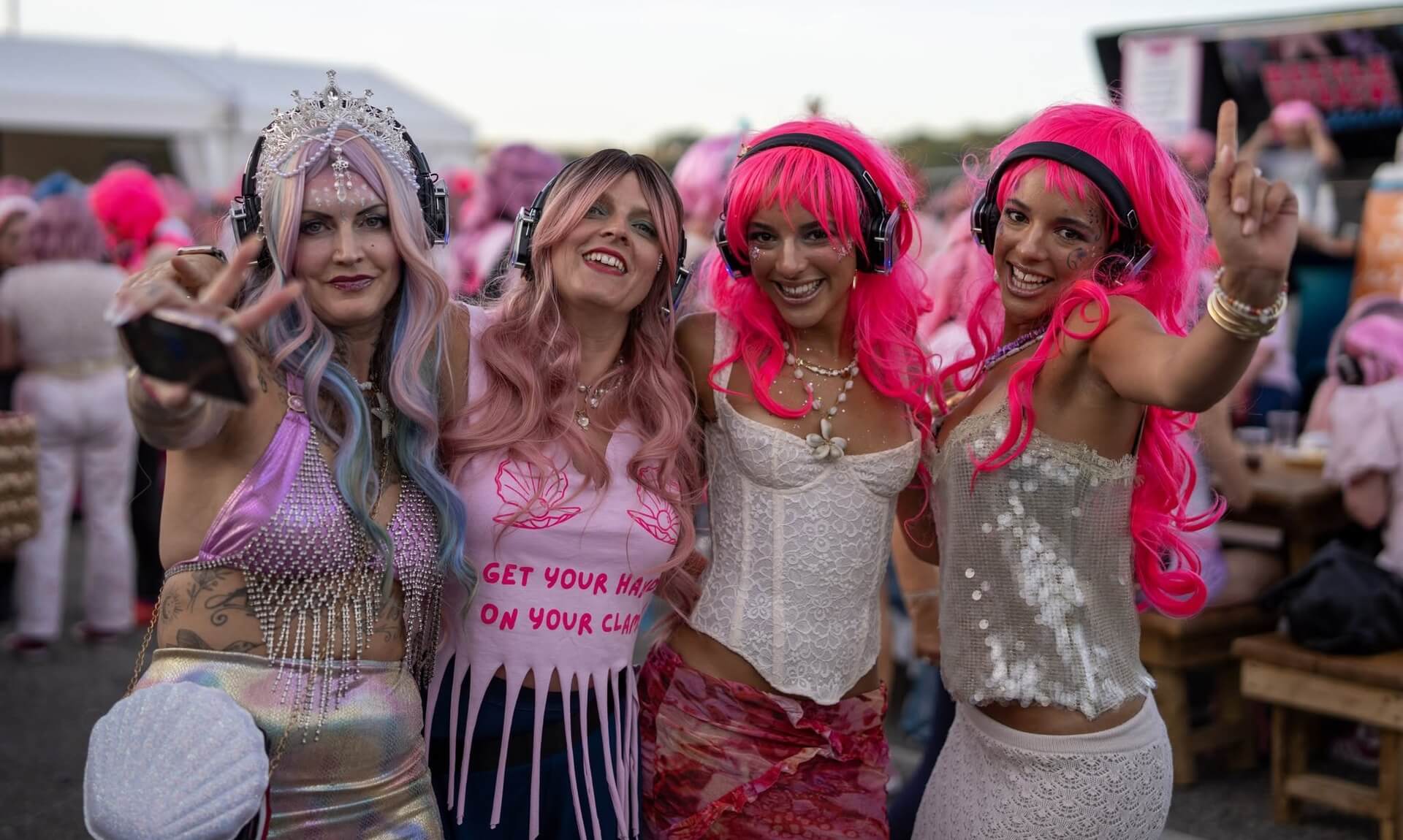 Four friends in pink and mermaid-themed wigs at the Falmouth Pink Wig Mermaid March