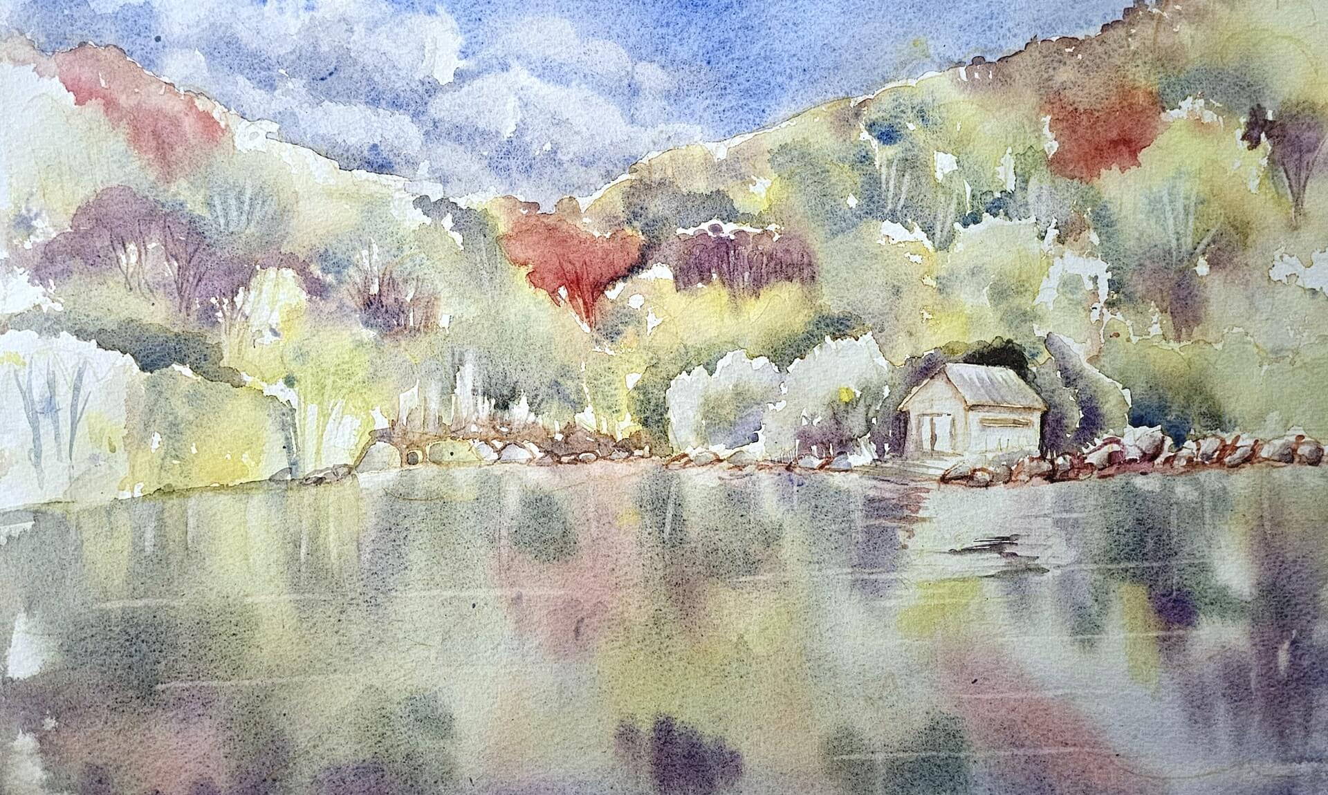 Watercolour painting of autumn trees reflected in water beside a boathouse