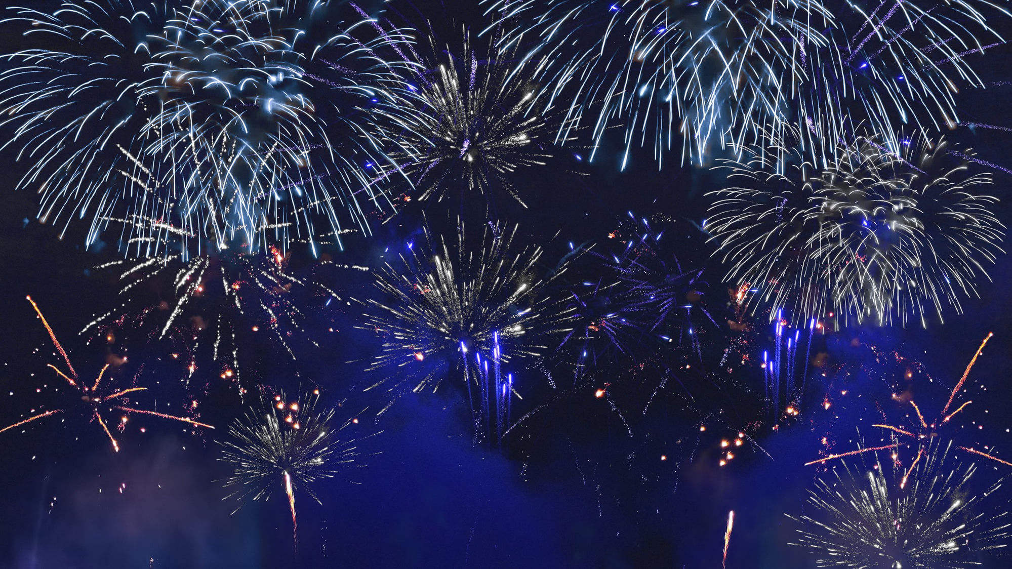 A display of fireworks lighting up the night sky in blue, white and gold