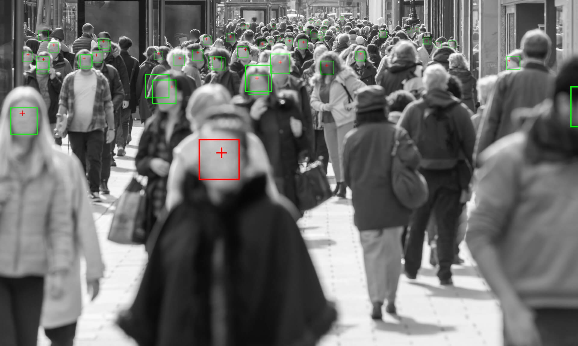 A crowded shopping street with green and red squares highlighting individual faces, illustrating live facial recognition technology