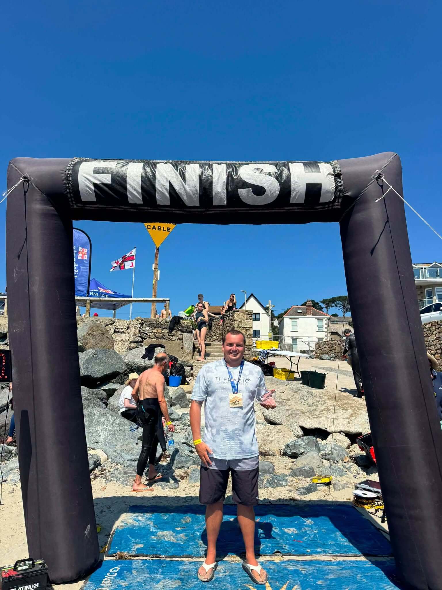 Matt Trewhella holding an award under a Finish arch after an open water swim