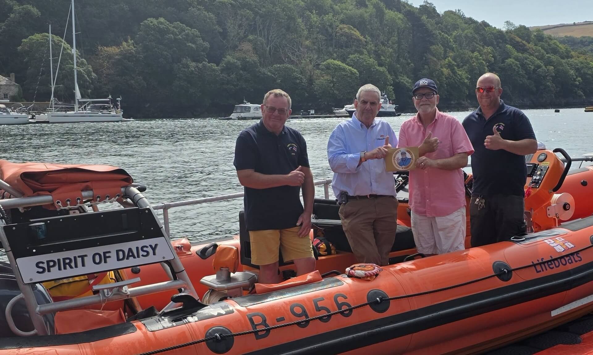 Fred Gardner presenting a cheque to Fowey RNLI crew members beside the station's inshore lifeboat