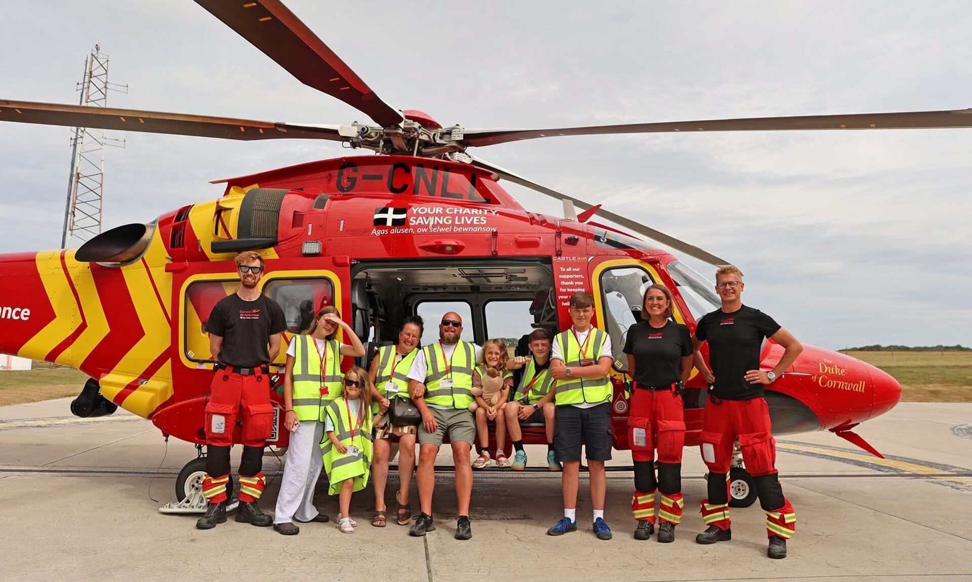 Freddie and his family with Cornwall Air Ambulance crew in front of the red AW169 helicopter