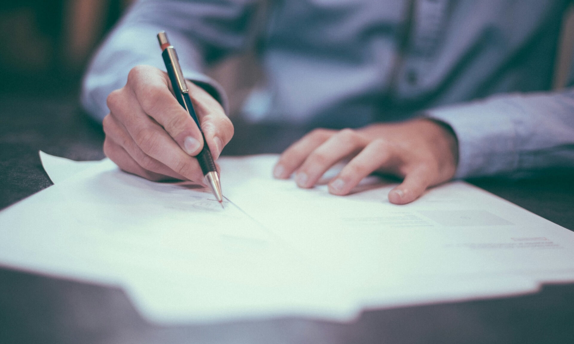 A hand writing on an exam paper with a pencil