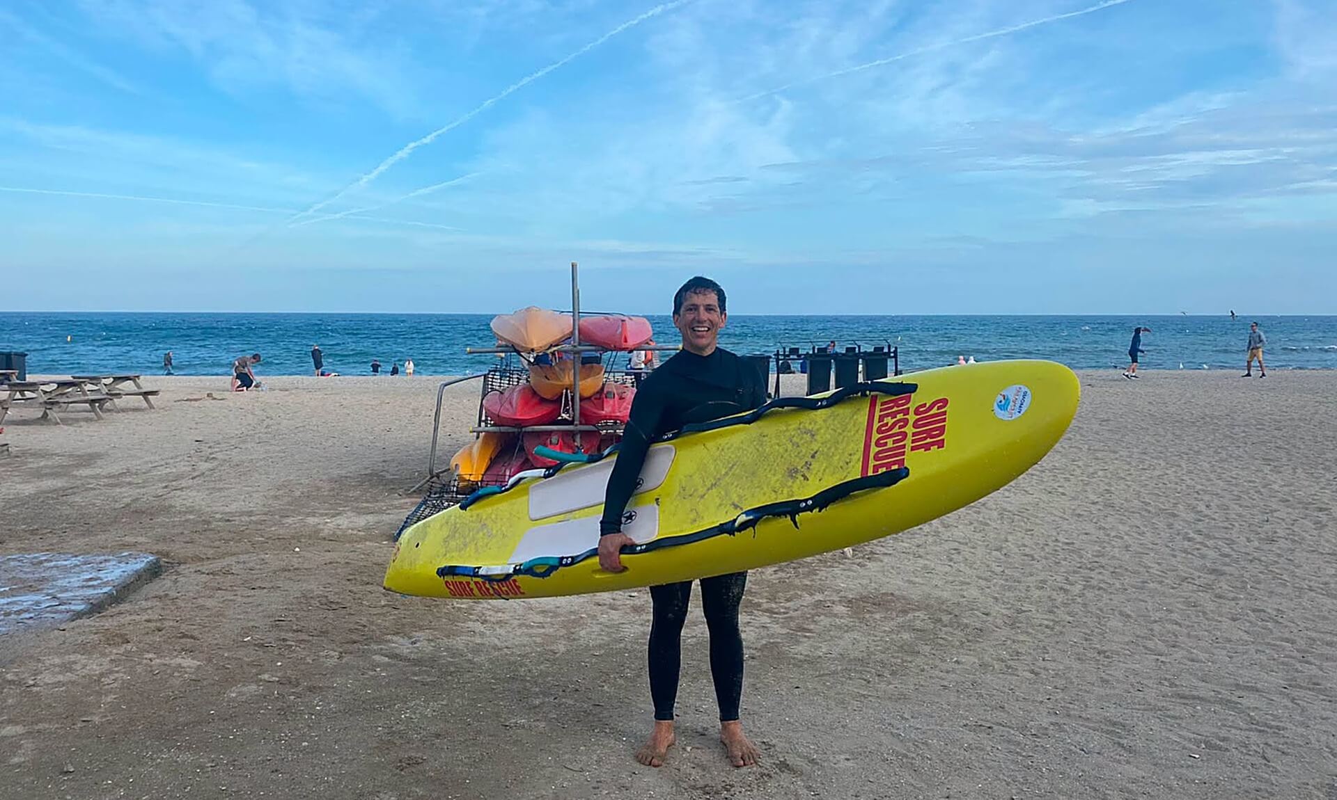 A Gyllyngvase Surf Life Saving Club volunteer on the beach with a surf rescue board