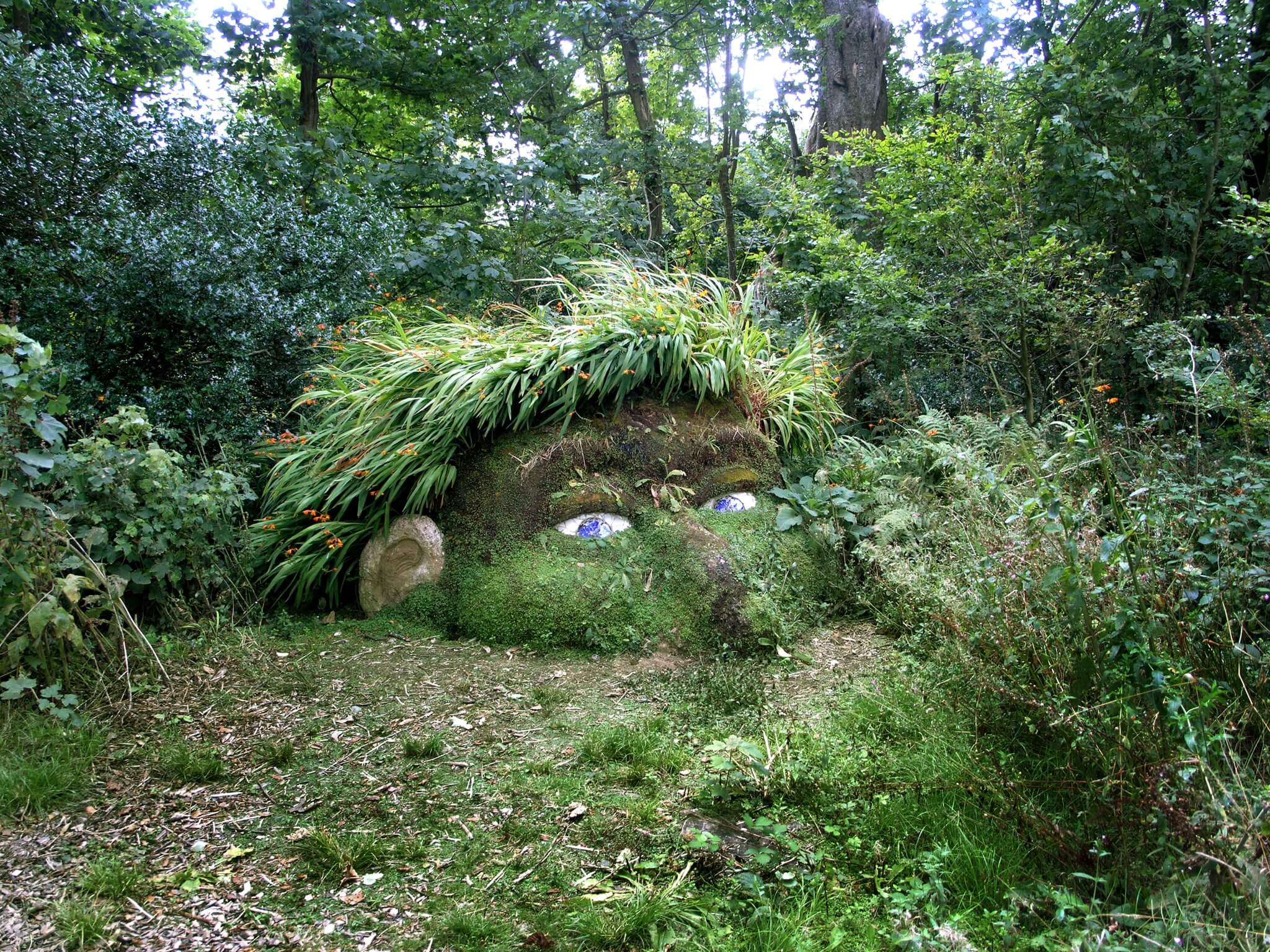 The Giant's Head sculpture at Heligan, mossed over with a mane of grass and blue eyes