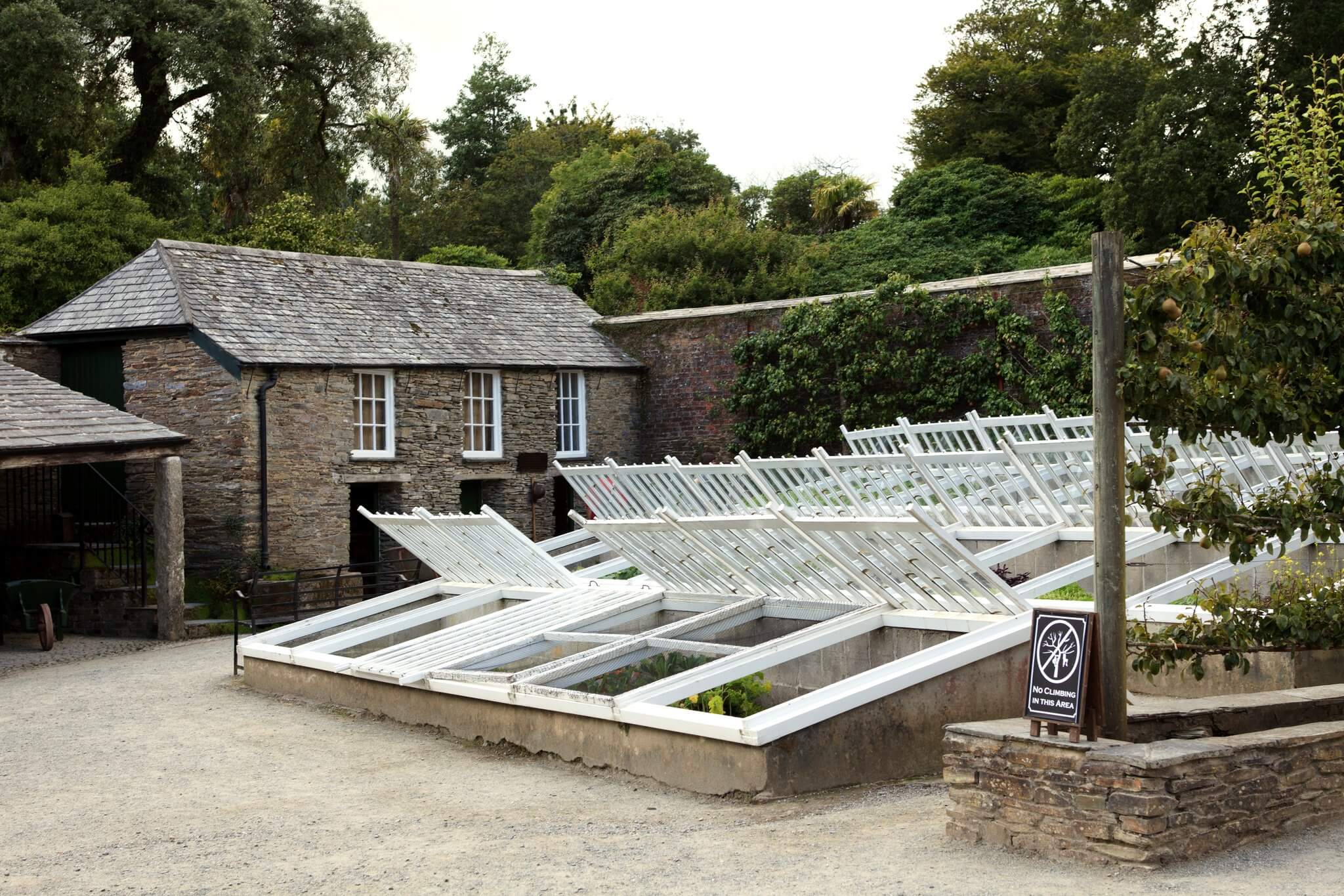 Restored glass melon-frames and the stone bothy in the productive gardens at Heligan