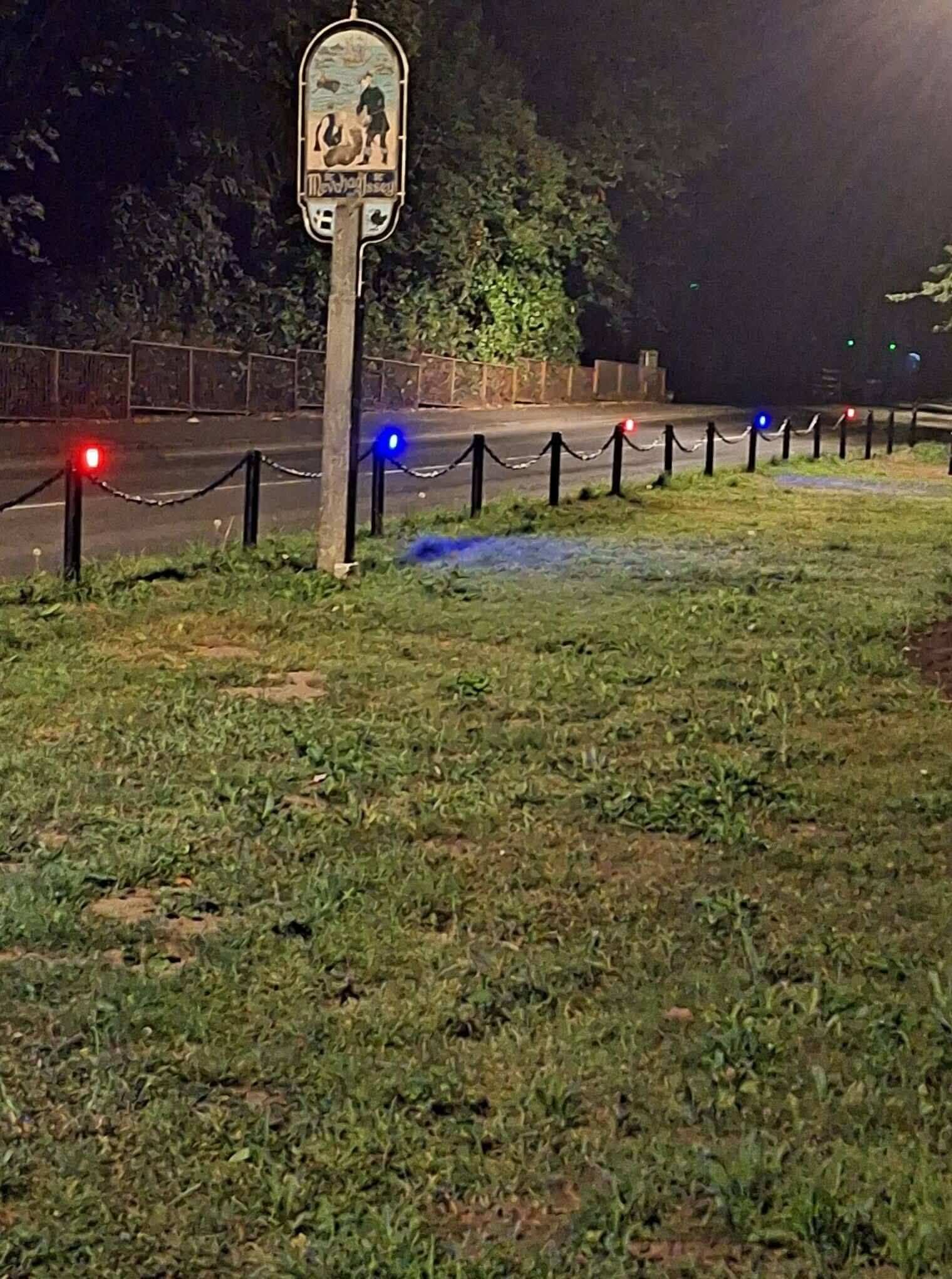 Red and blue lights along the bollards of Mevagissey's Cornerways and Valley Road garden area at night
