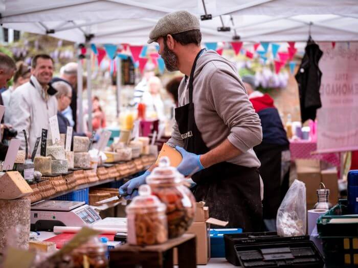 Trader serving cheese at a Cornish market stall