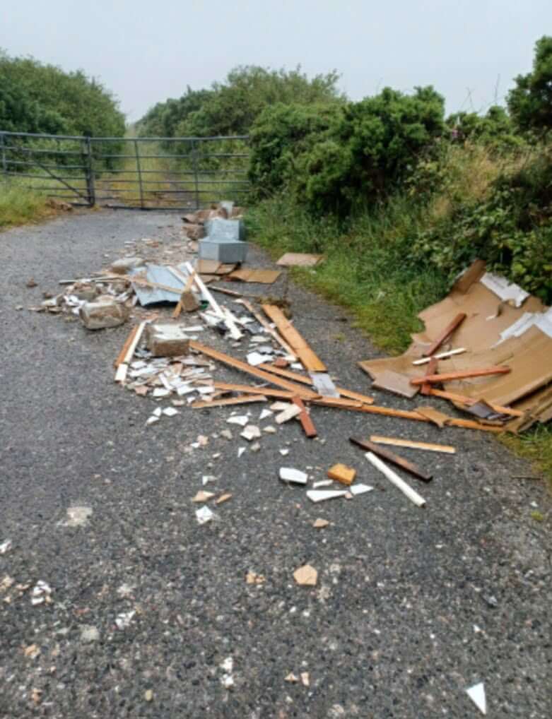 Fly-tipped building waste spread across a gated farm track at Belowda, near Roche
