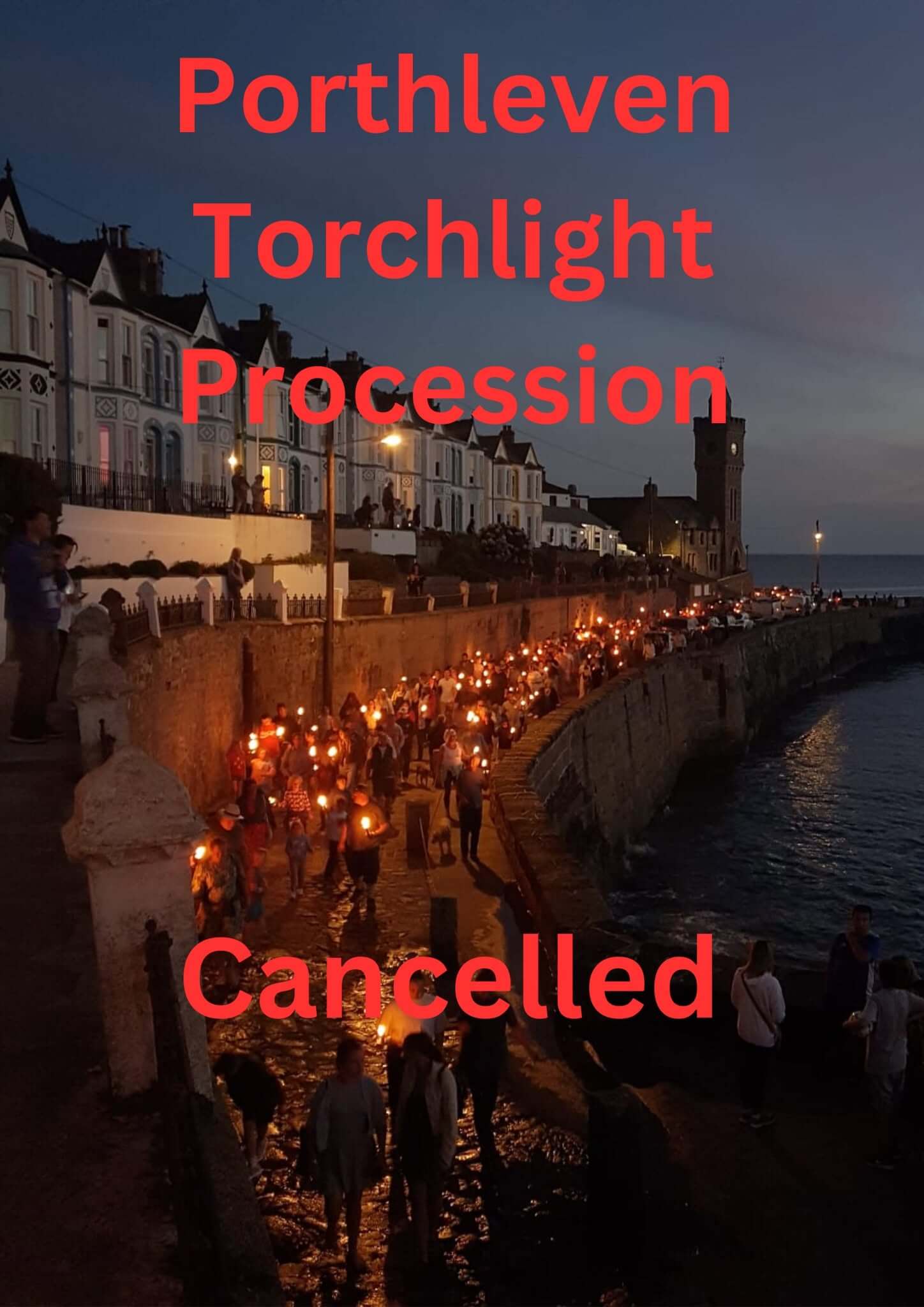 Crowds carrying lit torches along Porthleven harbour wall at night