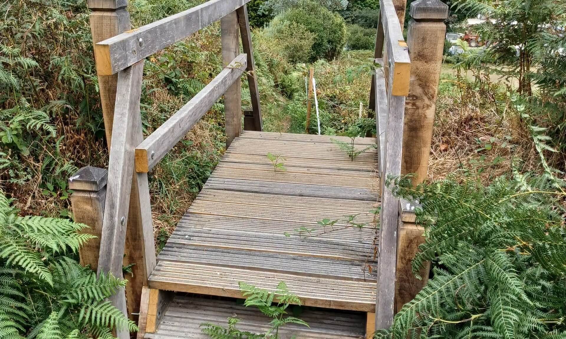 The new staircase stile at Higher Condurrow looking out over fields towards a former mining monument