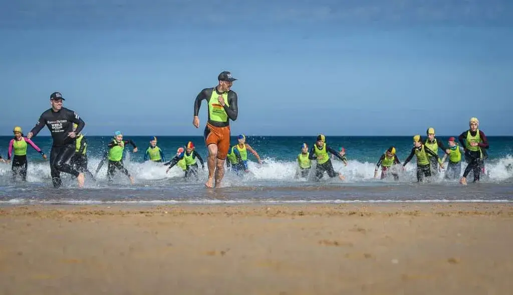 Nippers and coaches running out of the surf at Holywell Bay during a Surf Life Saving GB clinic