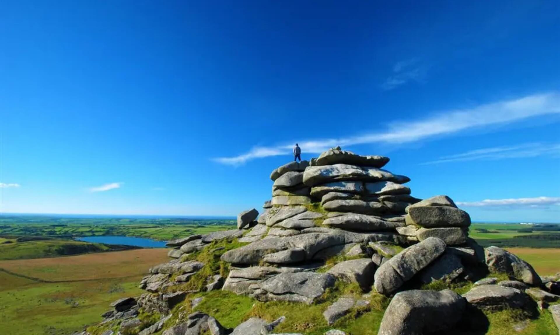 A walker standing on the granite summit of Rough Tor on Bodmin Moor