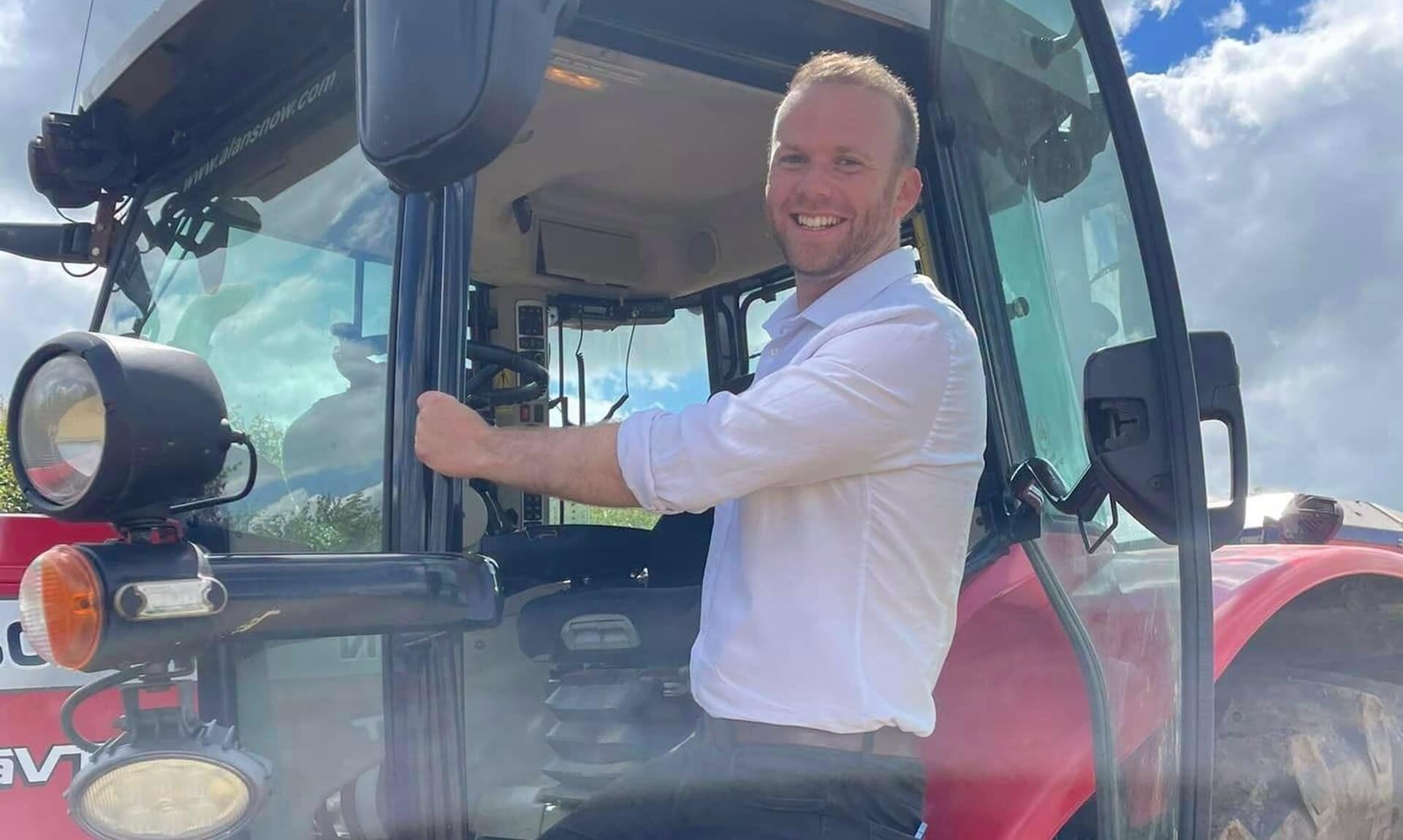 Ben Maguire MP standing on the step of a red tractor in North Cornwall