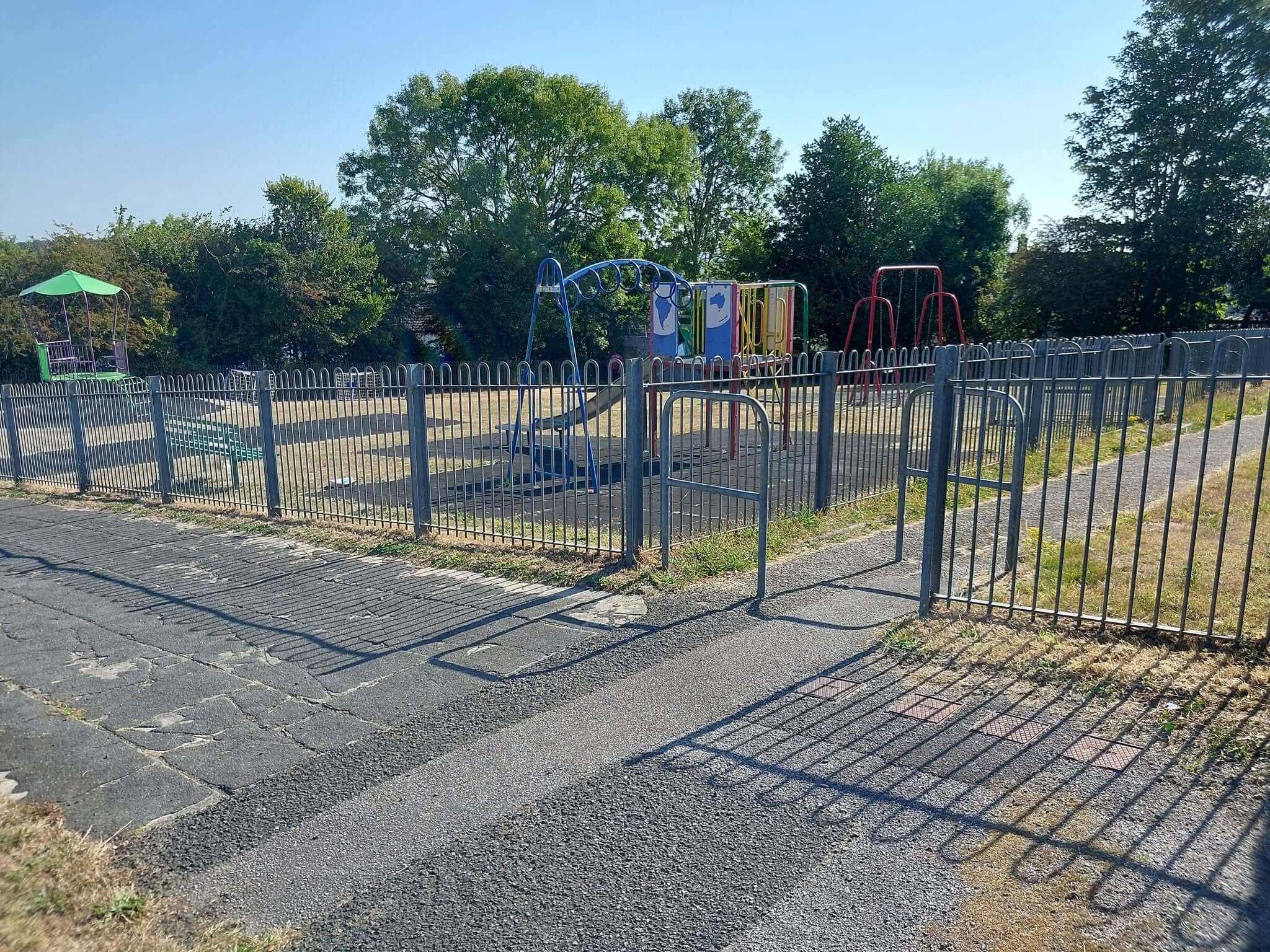Playground at Behenna Drive park in the Malabar area of Truro, with swings and a climbing frame behind metal railings