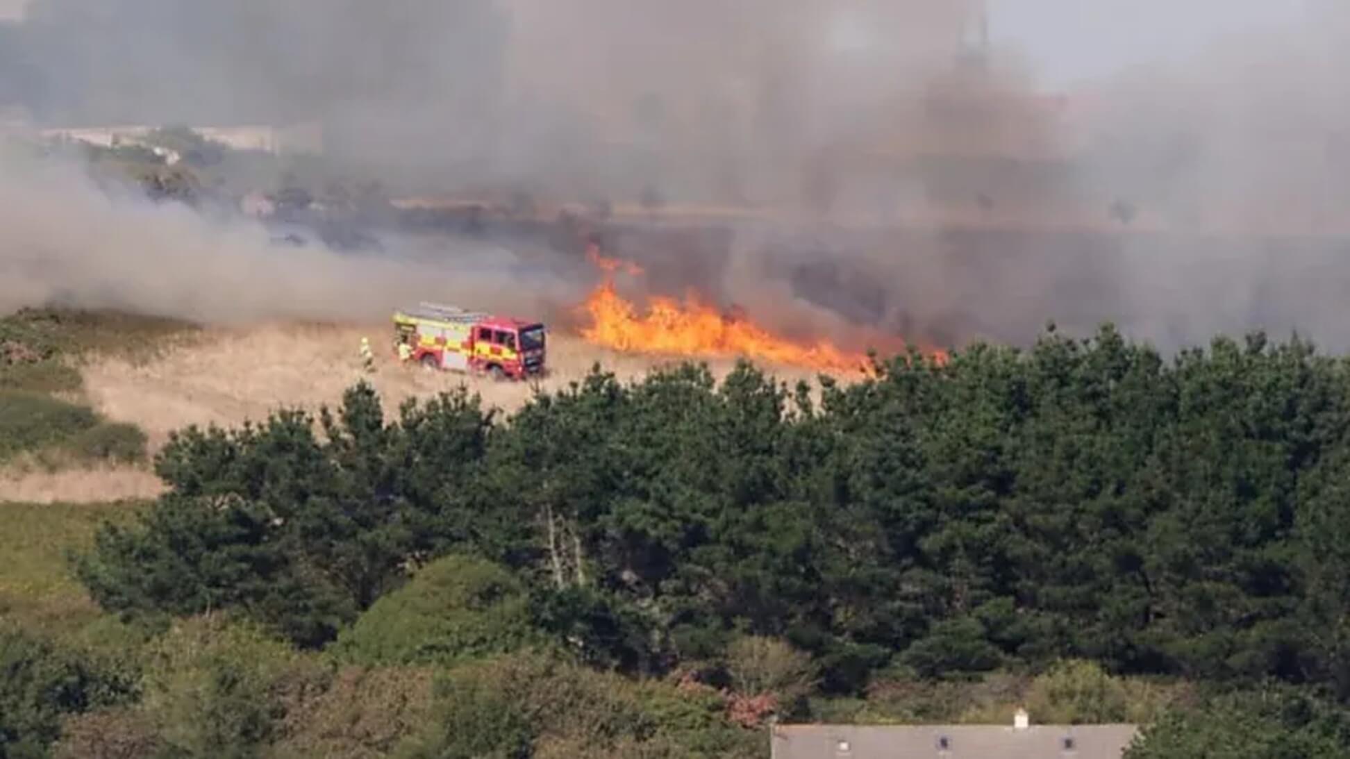 Cornwall Fire and Rescue Service fire engine beside wildfire flames at Mawgan Porth