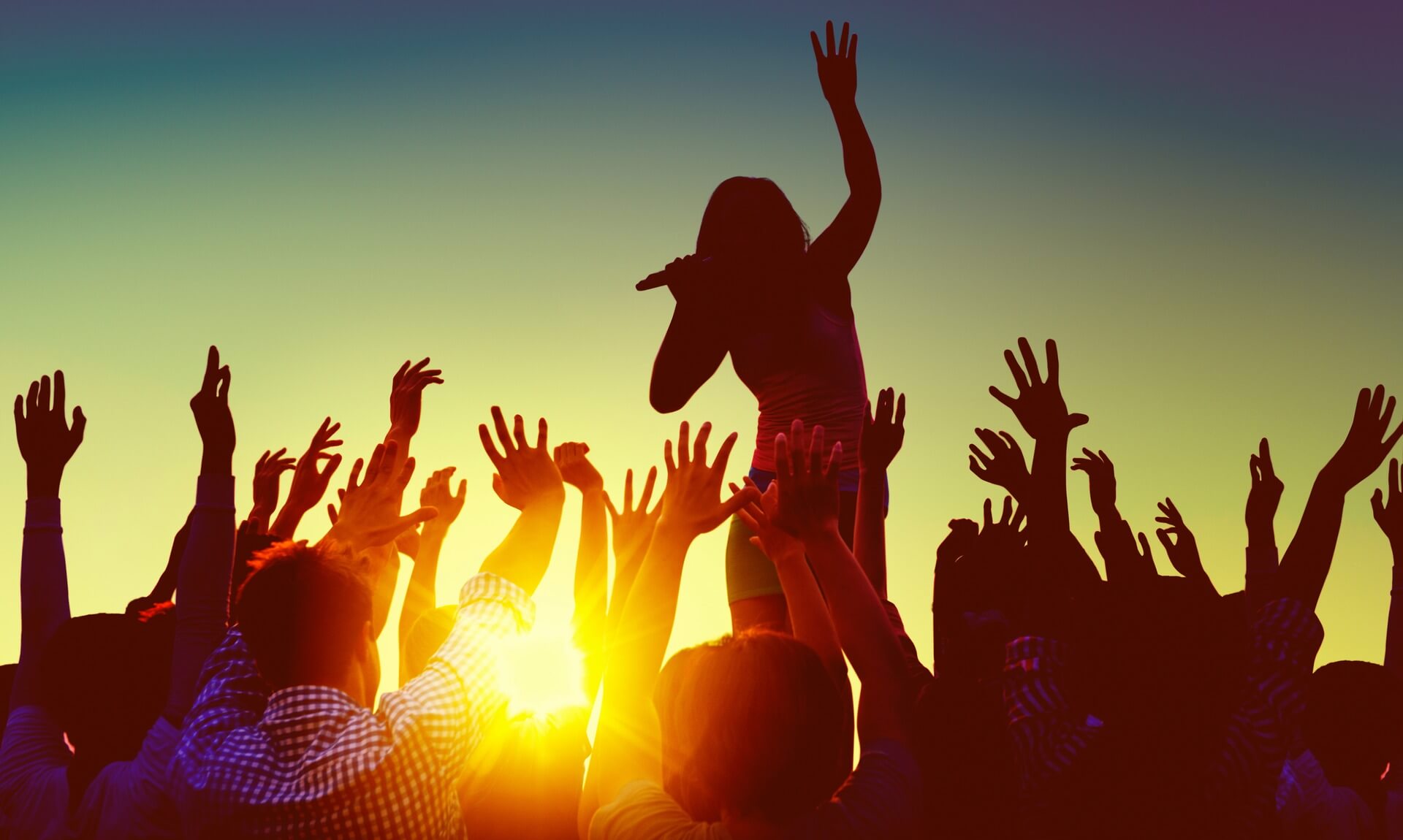 Crowd with hands raised at a festival at sunset