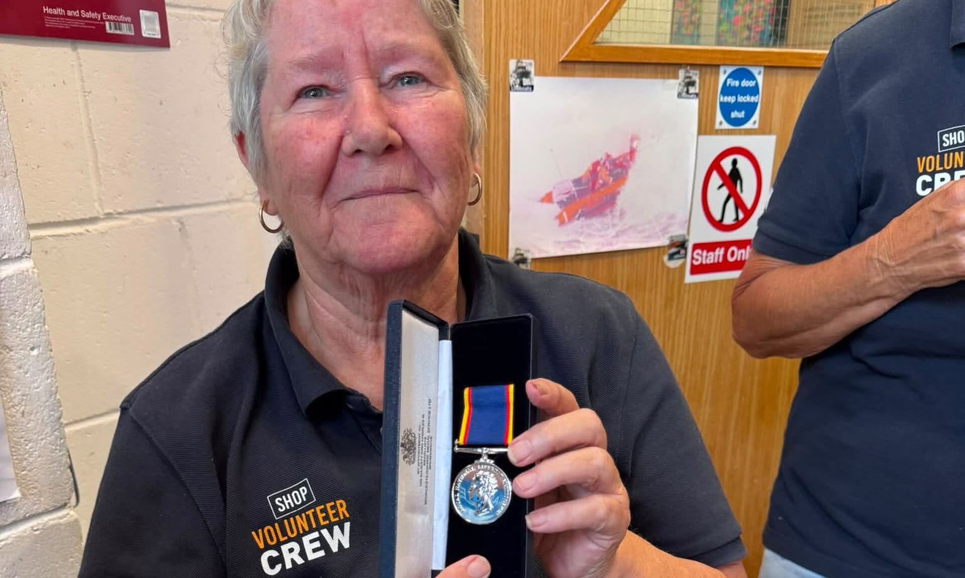 Janet Kearton holding her RNLI Long Service Medal at Newquay lifeboat station