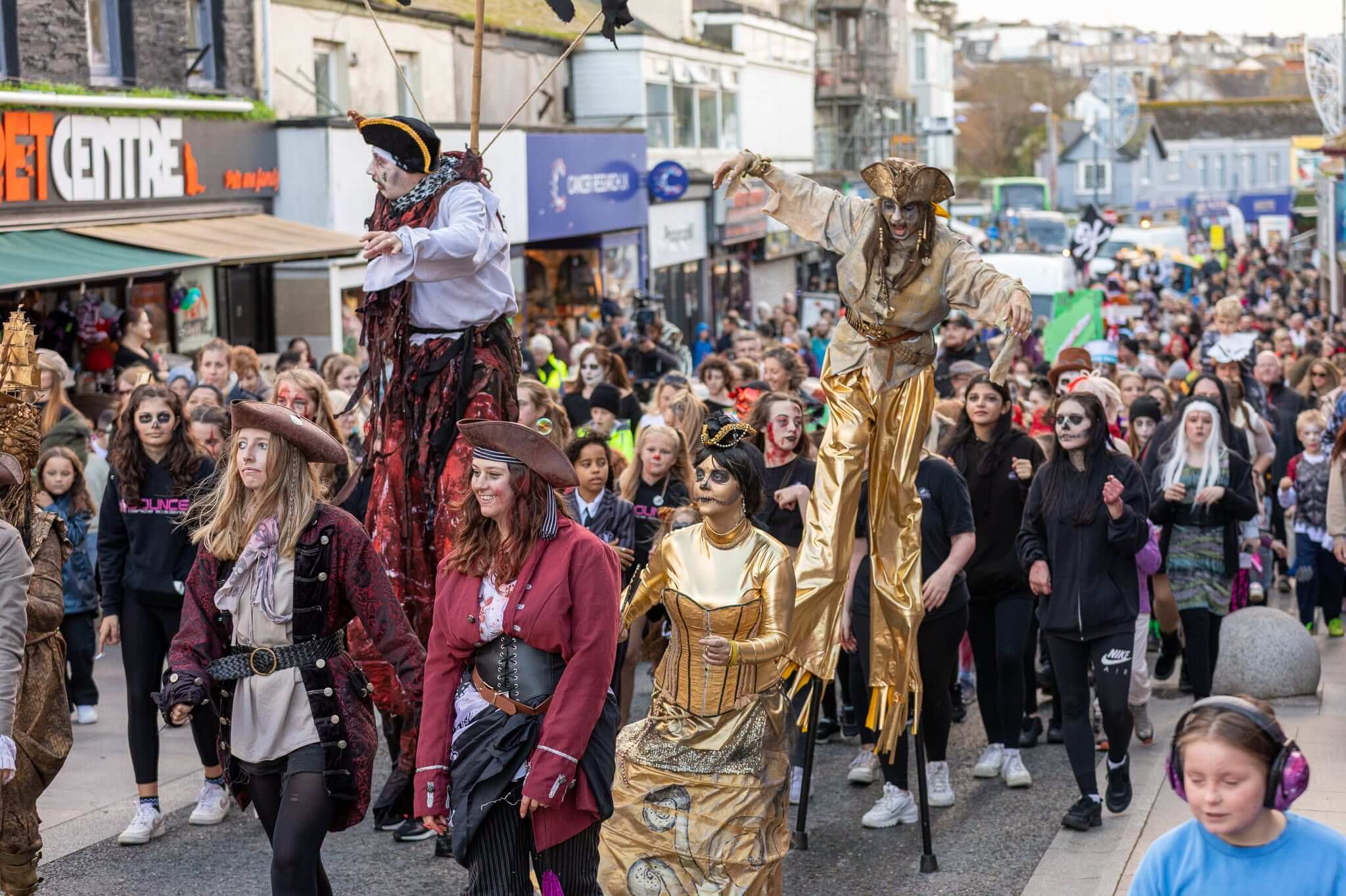 Costumed stilt-walkers and crowds at Newquay's Zombie Crawl