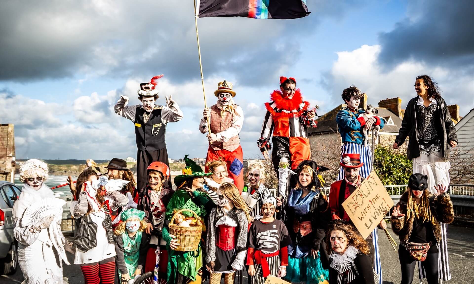 Stilt walkers and painted performers lead the flag at the Spooky Newquay Zombie Crawl