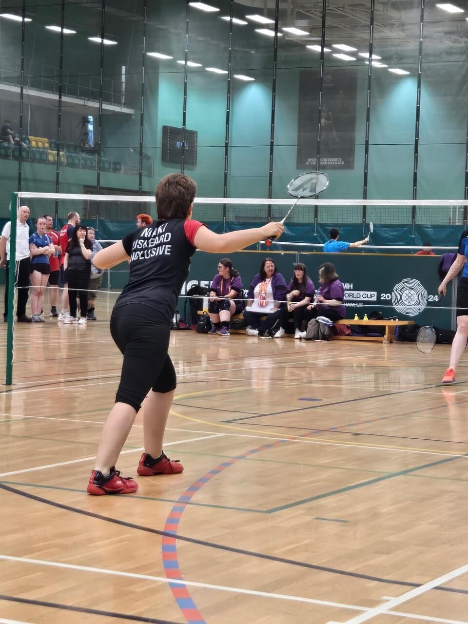 Nikki Welch playing badminton, wearing a Liskeard All Inclusive shirt