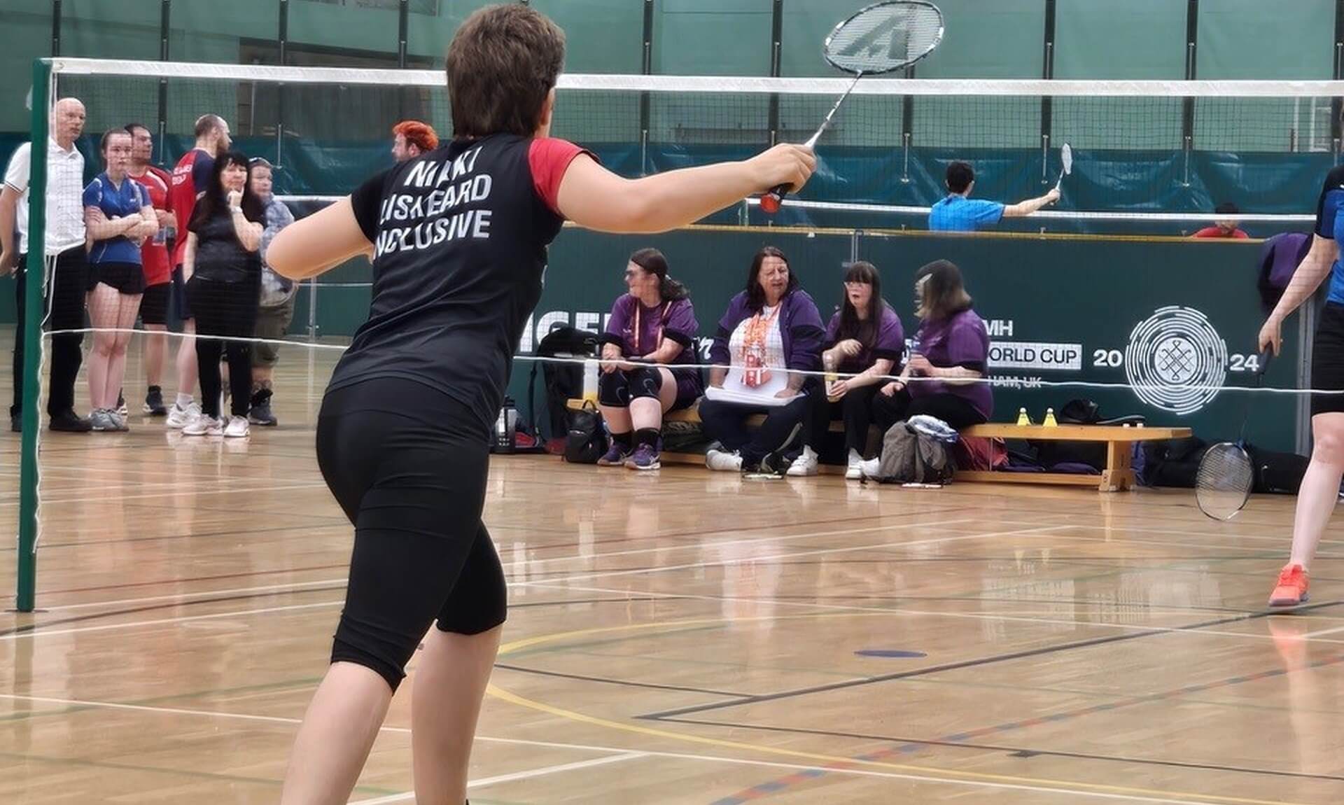 Nikki Welch playing badminton, wearing a Liskeard All Inclusive shirt