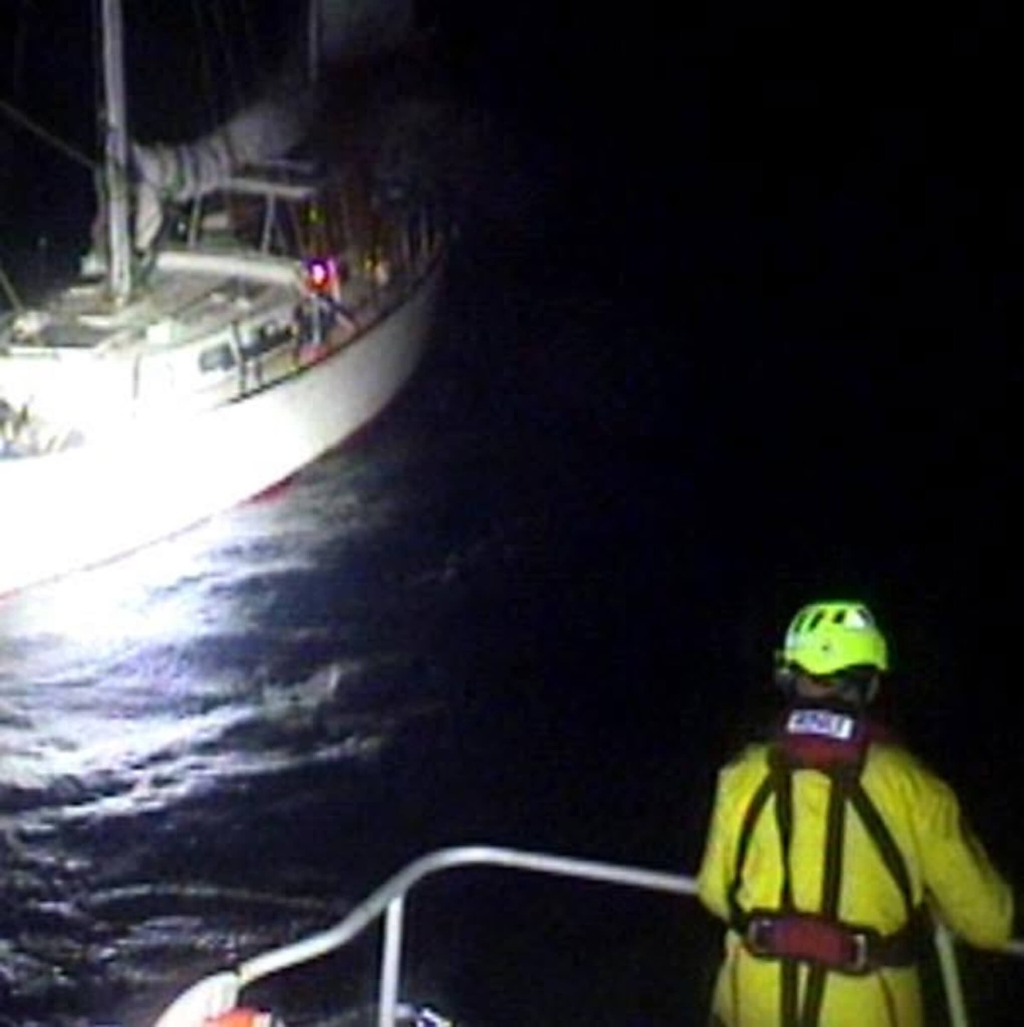 Padstow RNLI lifeboat crew member beside stricken yacht off Trevose Head at night